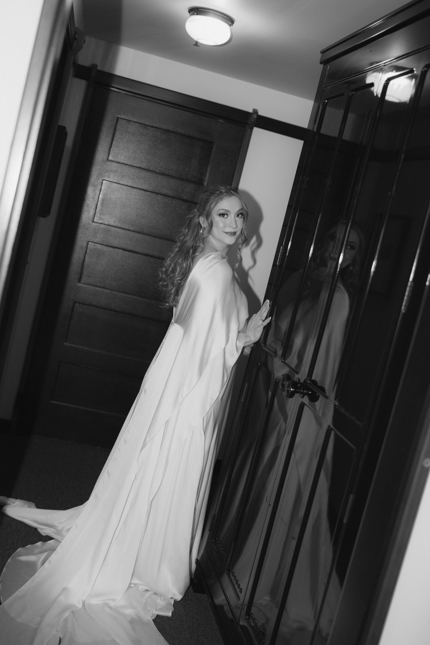 Dramatic black and white photos of bride in flowing dress and veil walking down dark hallway.