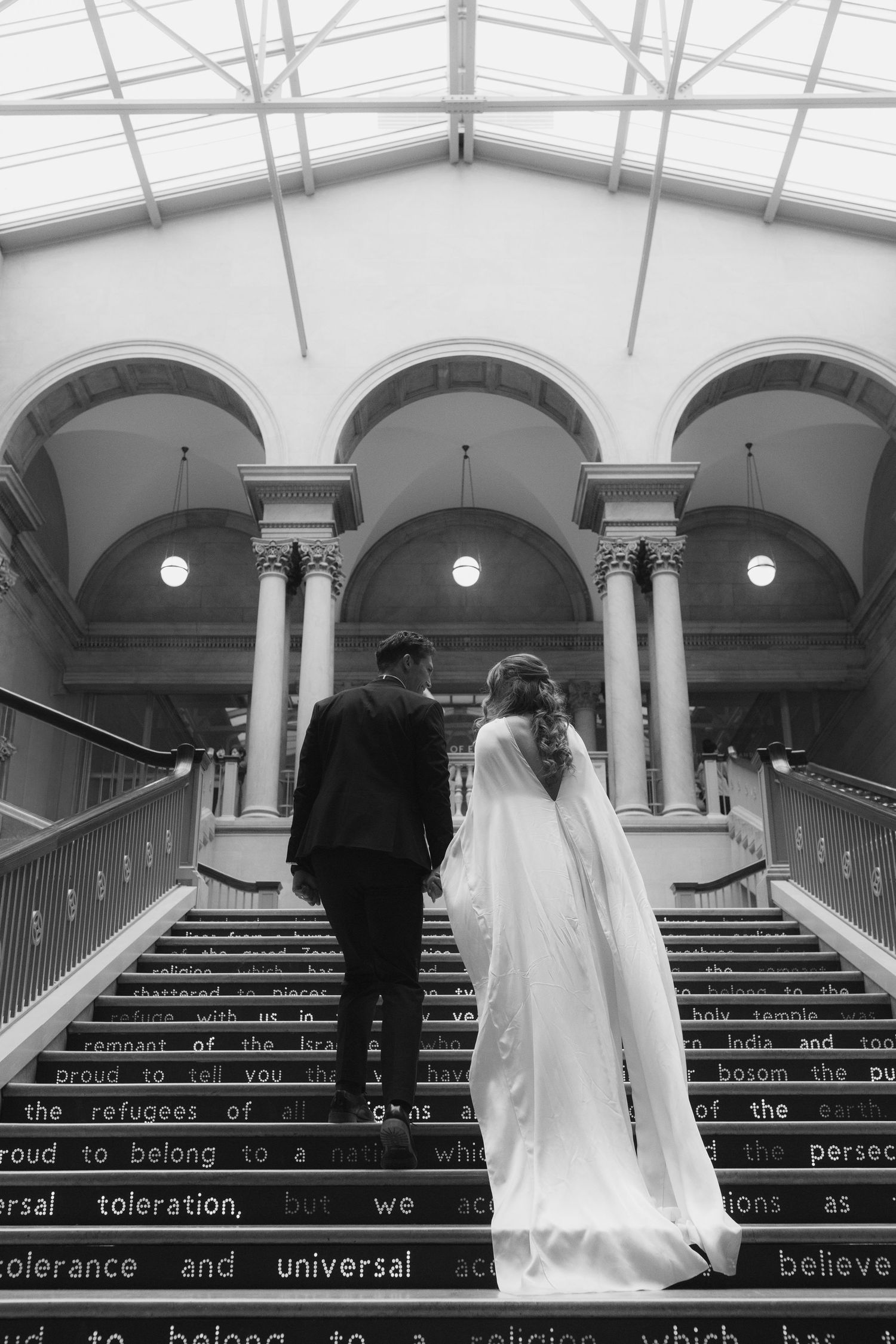 Black and white wedding photos on grand staircase with text written on steps.