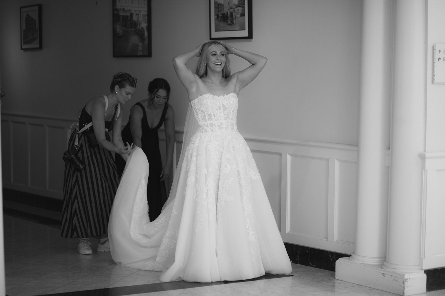 A row of white wedding dresses displayed on hangers in a bridal boutique fitting room.