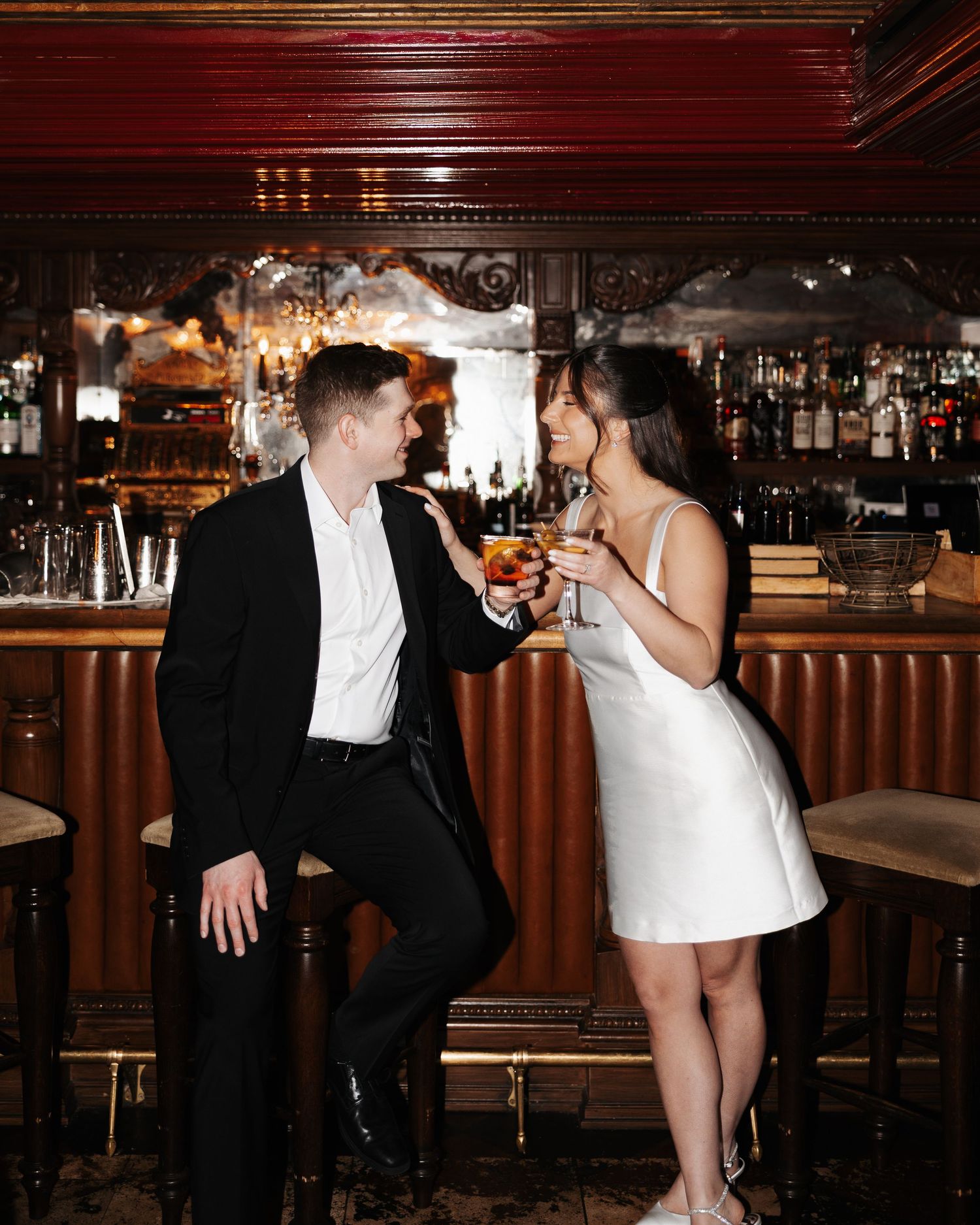 A couple in formal attire shares an intimate moment at a dimly lit bar counter.