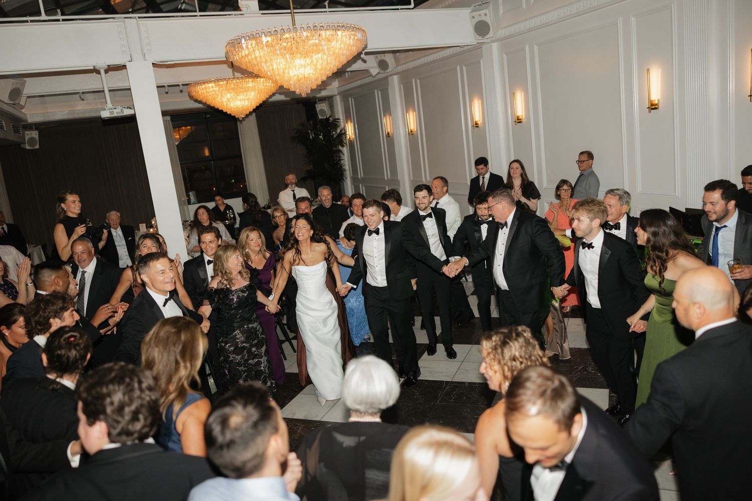 Elegant wedding reception with guests surrounding the couple on a dance floor in a formal ballroom.