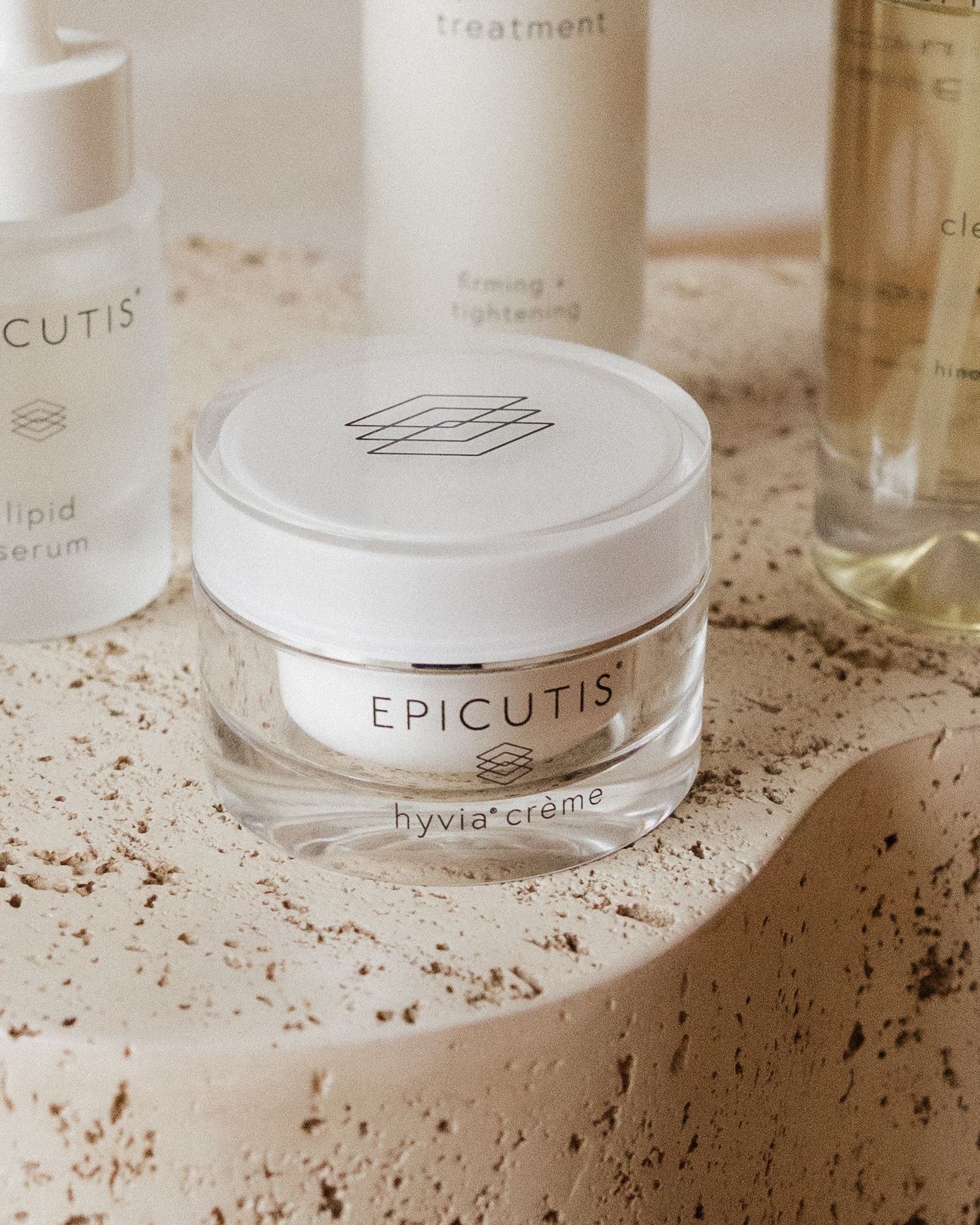 Collection of luxury skincare products from Epicutis brand arranged on textured surface.