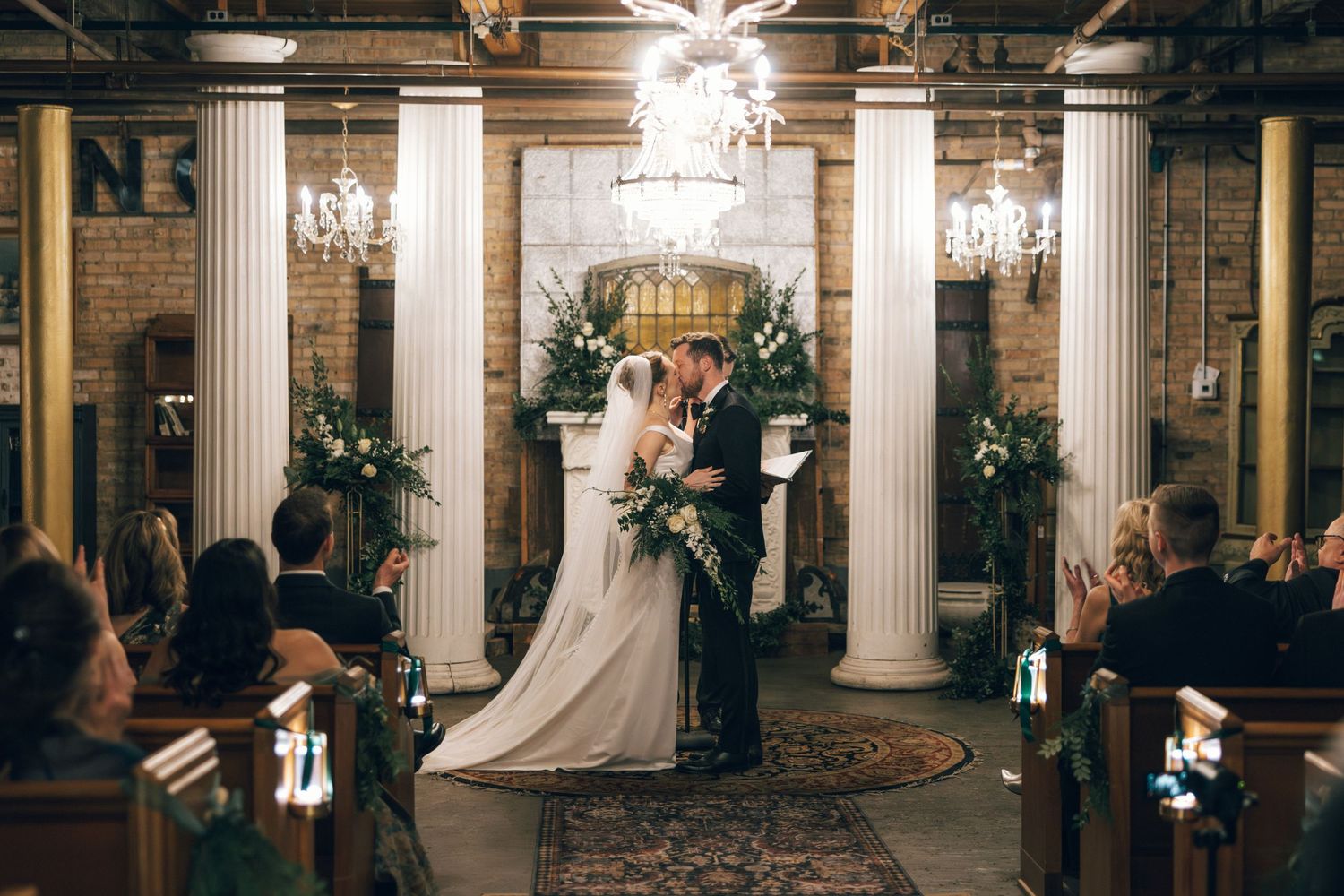 Elegant wedding reception venue with white columns and chandeliers creating a grand ballroom atmosphere.