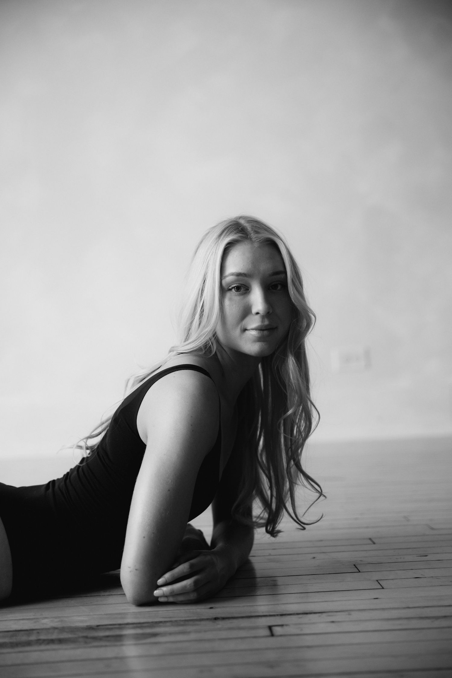A black and white photo series showing someone lying on a wooden floor in various contemplative poses.