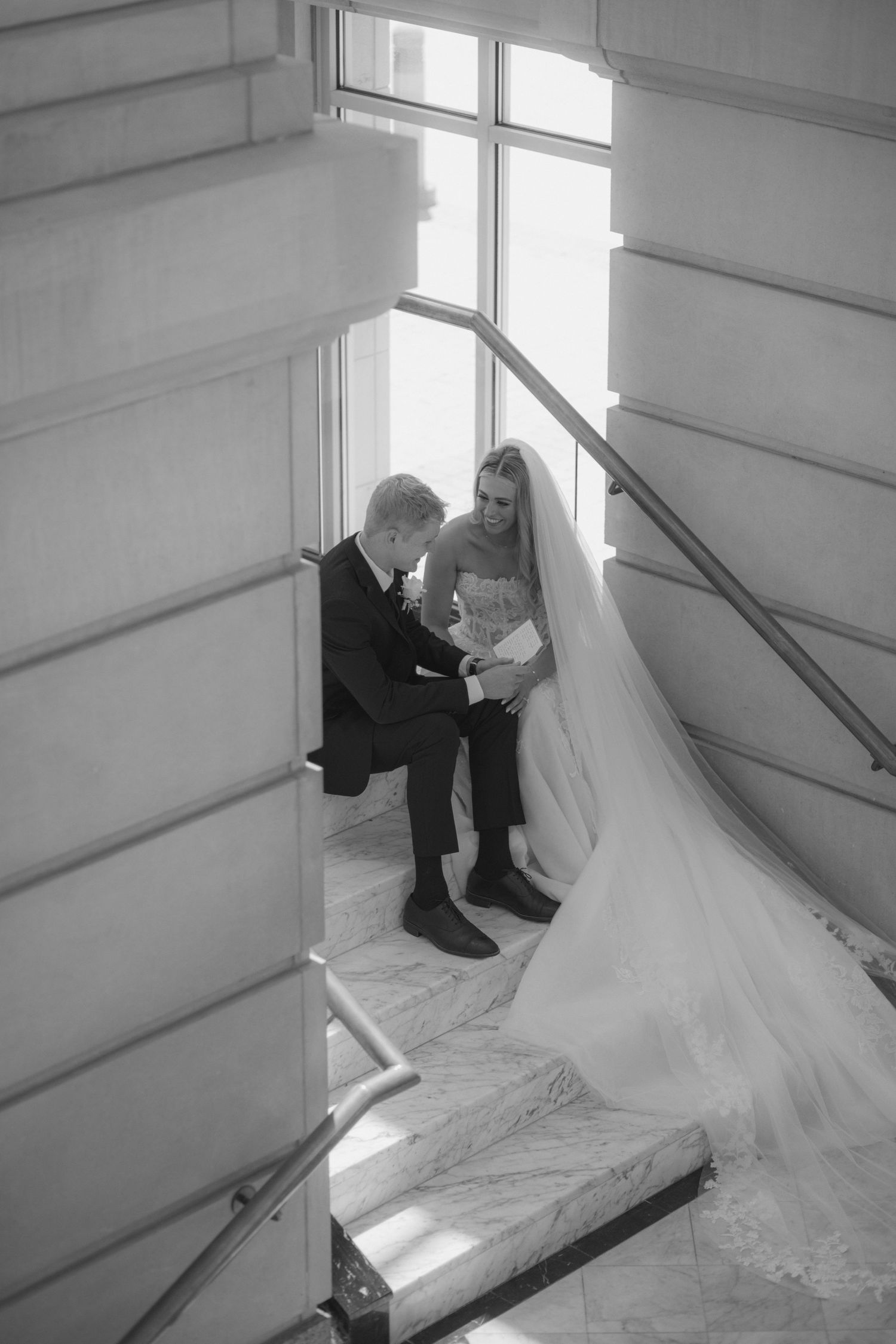 Wedding photo series on a bright staircase with natural window lighting.