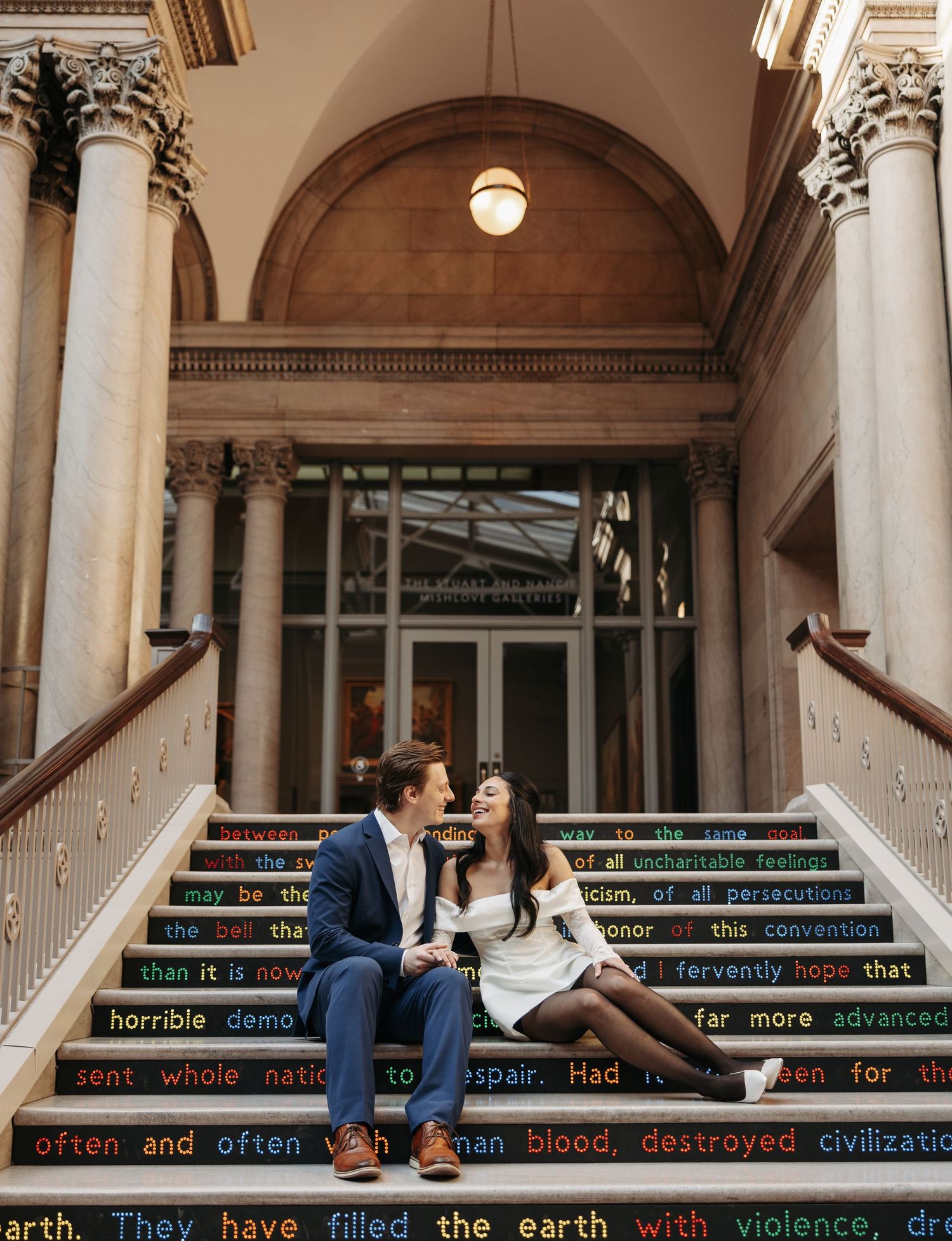 Couple sitting on ornate staircase with decorative text elements.