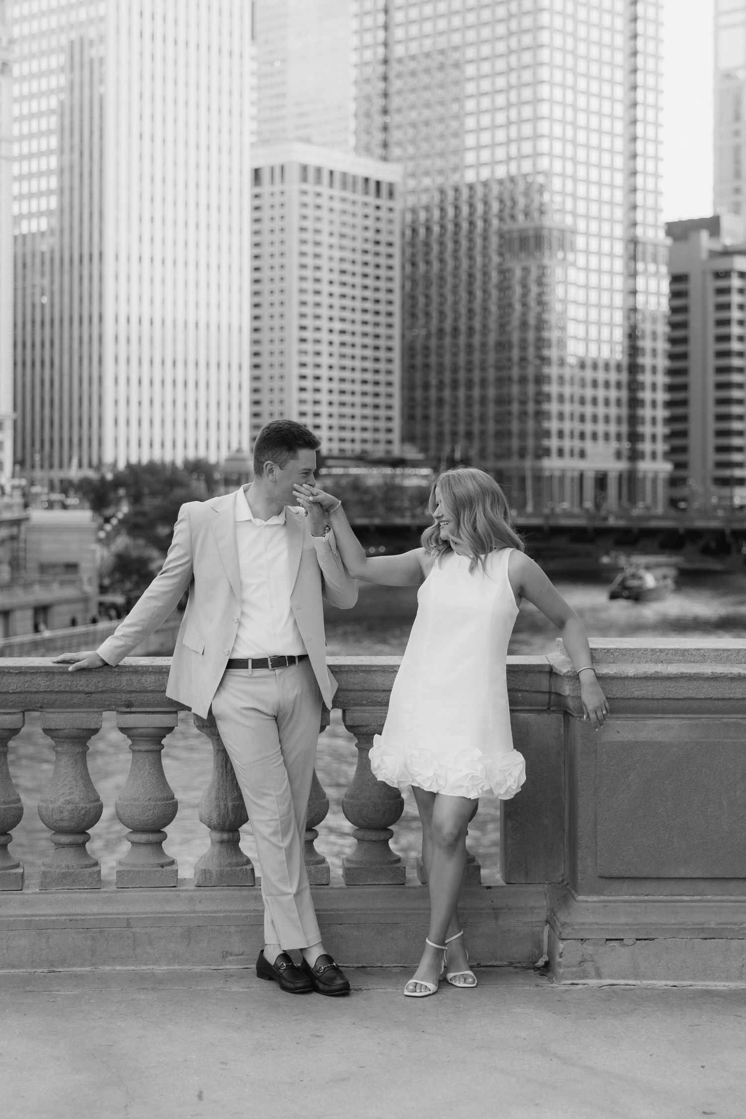 Couple sharing a romantic moment on stone bridge with Chicago city skyline in background.
