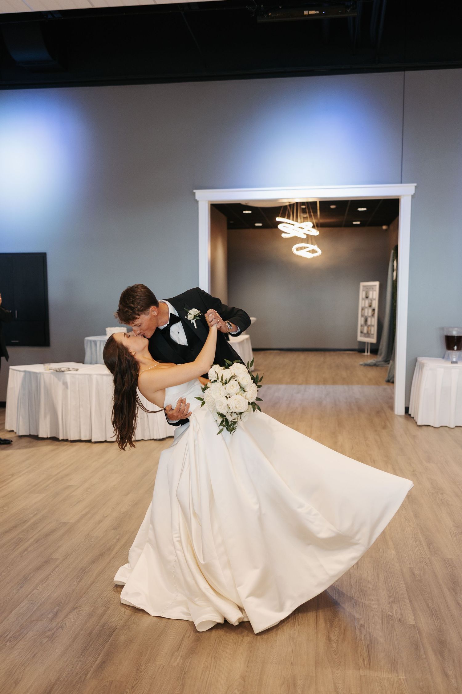 Bride and groom share a romantic dip kiss on the dance floor during their first dance at wedding reception.