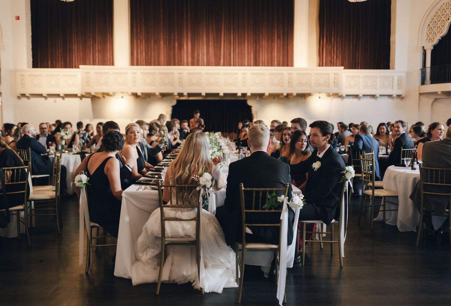 Wedding reception venue with dark curtains and elegant table settings.