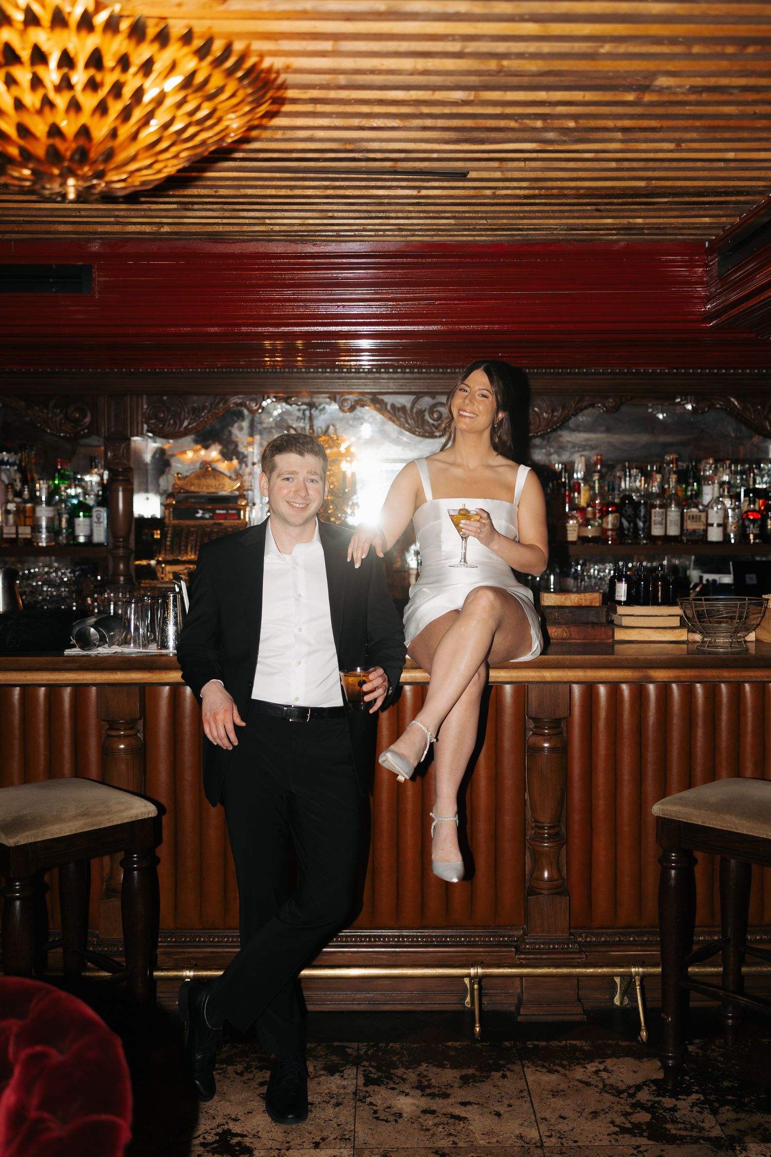 People dancing and socializing at a dimly lit bar with wood paneled walls and vintage decor.