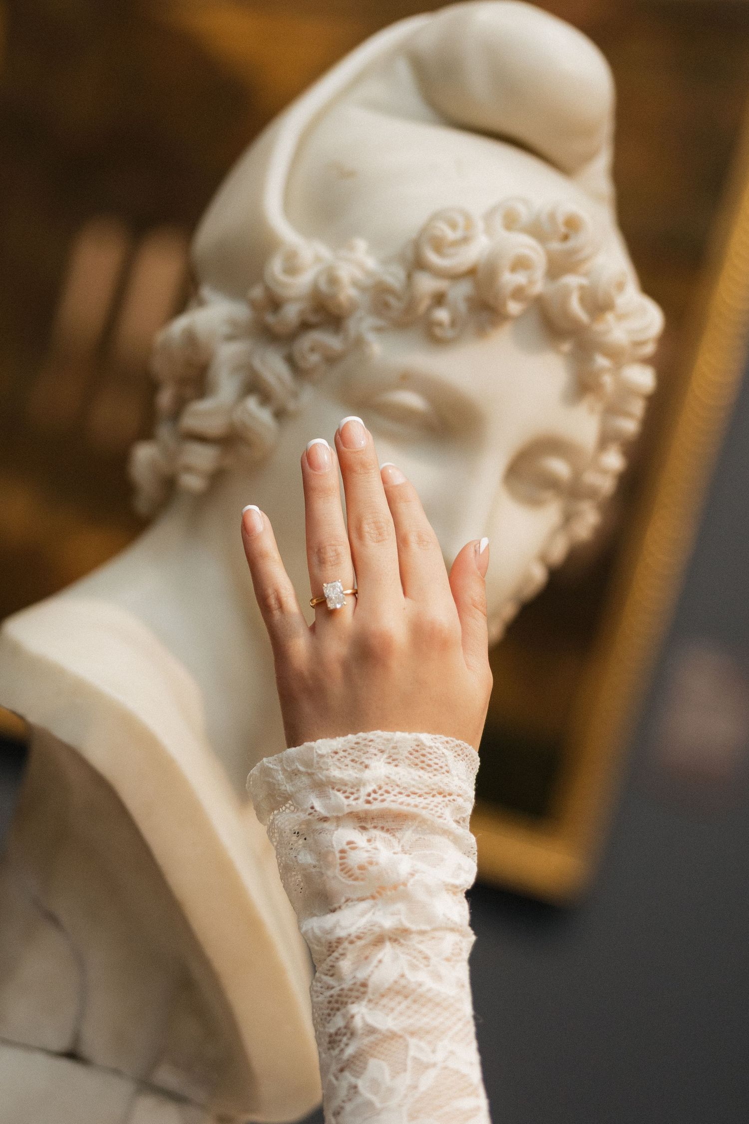 Close-up of a delicate lace-covered hand with an engagement ring.