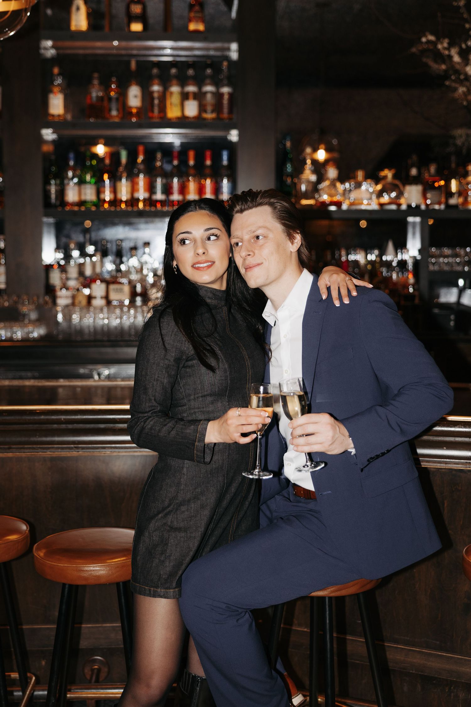 Two people enjoy champagne together at an upscale bar counter.