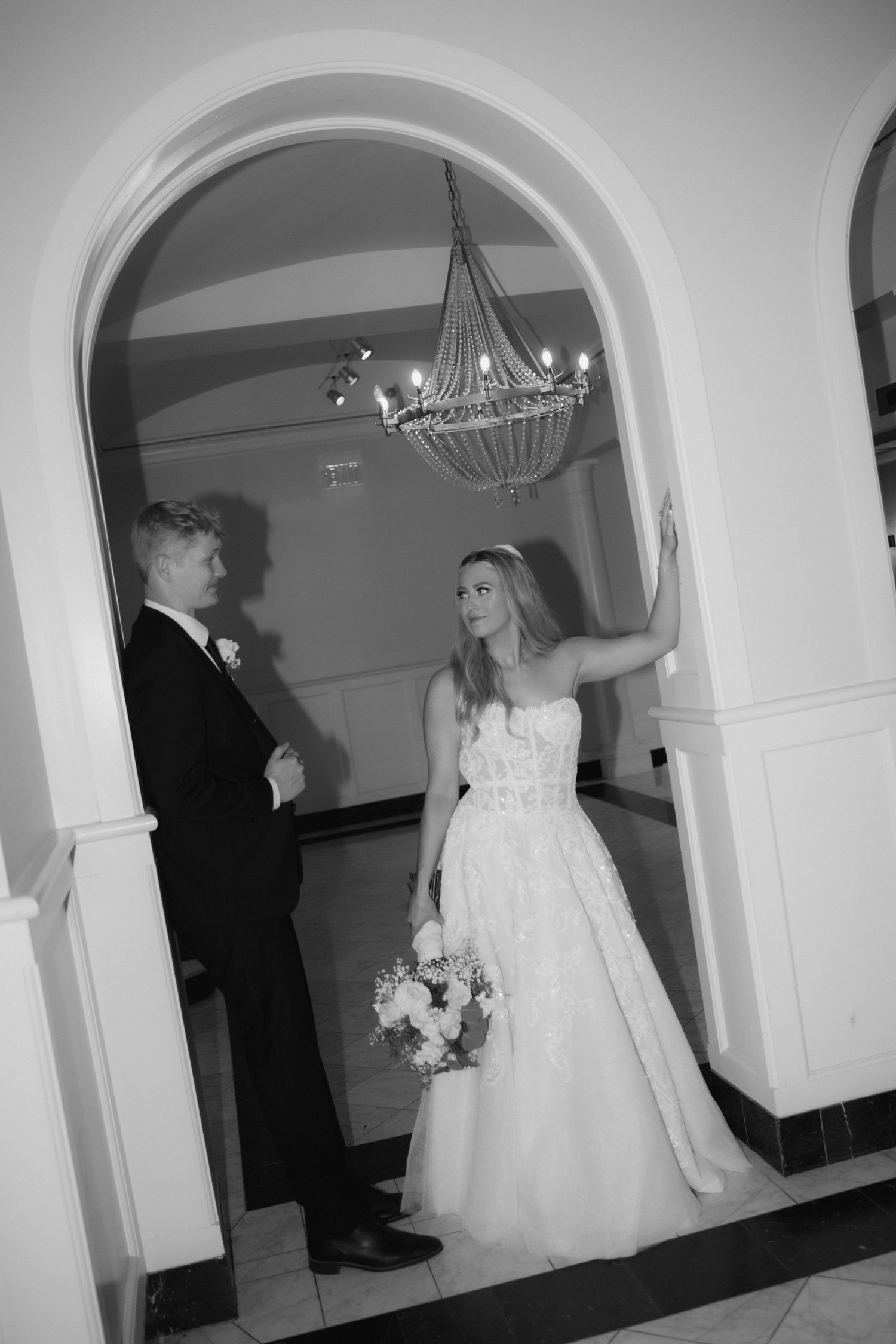 Black and white photos of a wedding ceremony in an elegant arched hallway.
