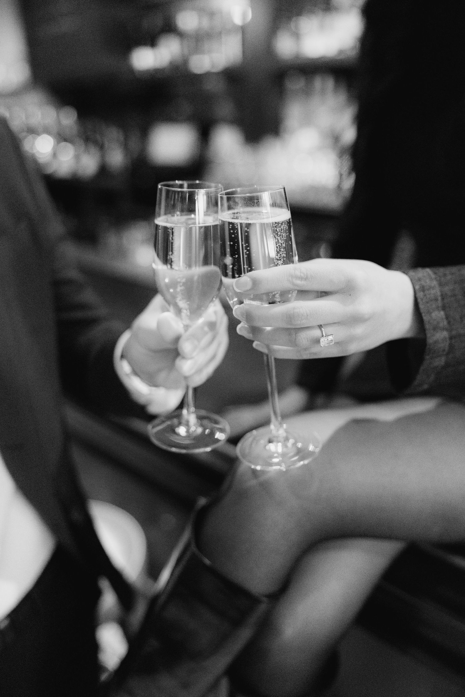 Black and white photo of wine glasses clinking together in celebration.