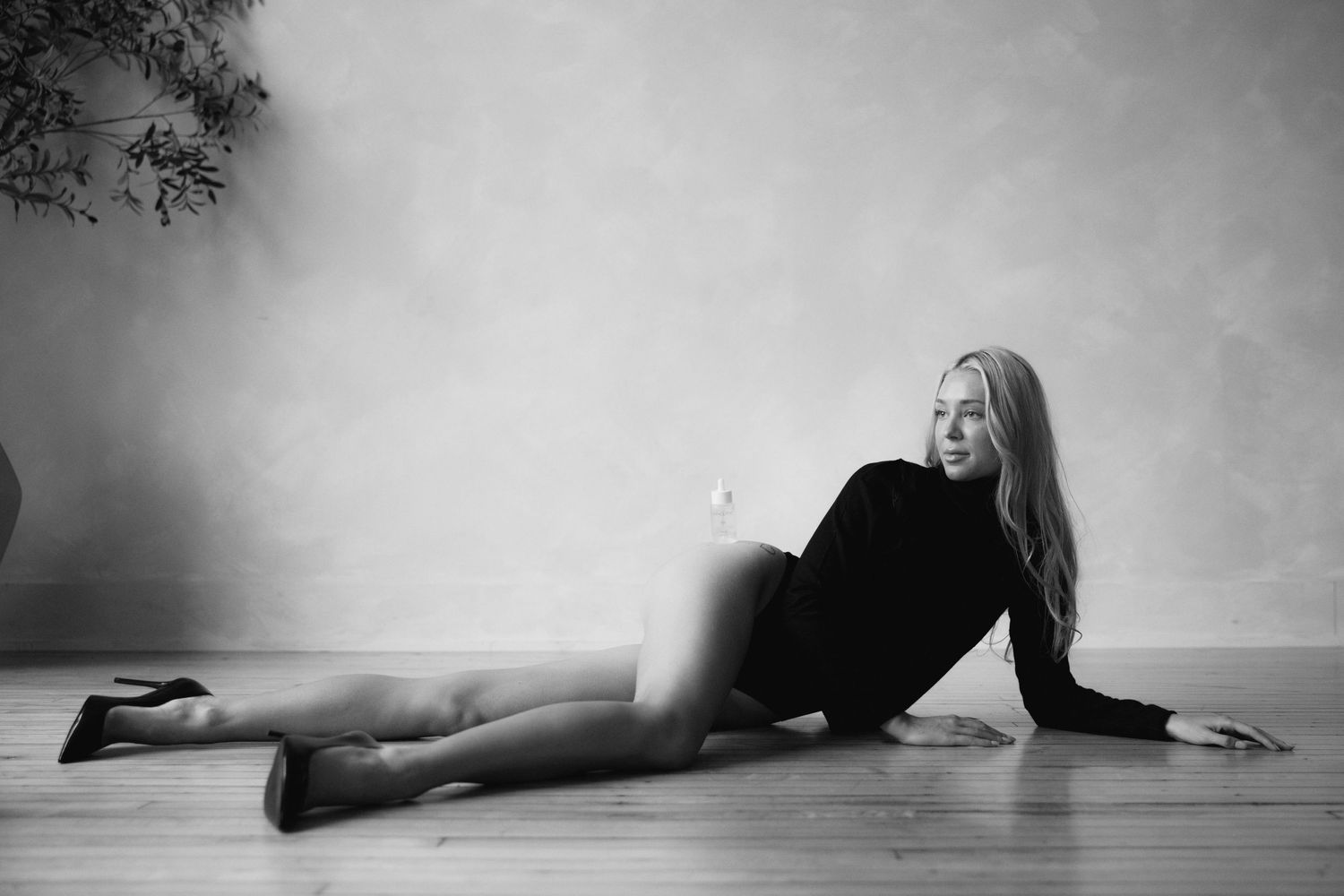 Black and white artistic photo sequence showing a figure lying on a wooden floor in different poses.