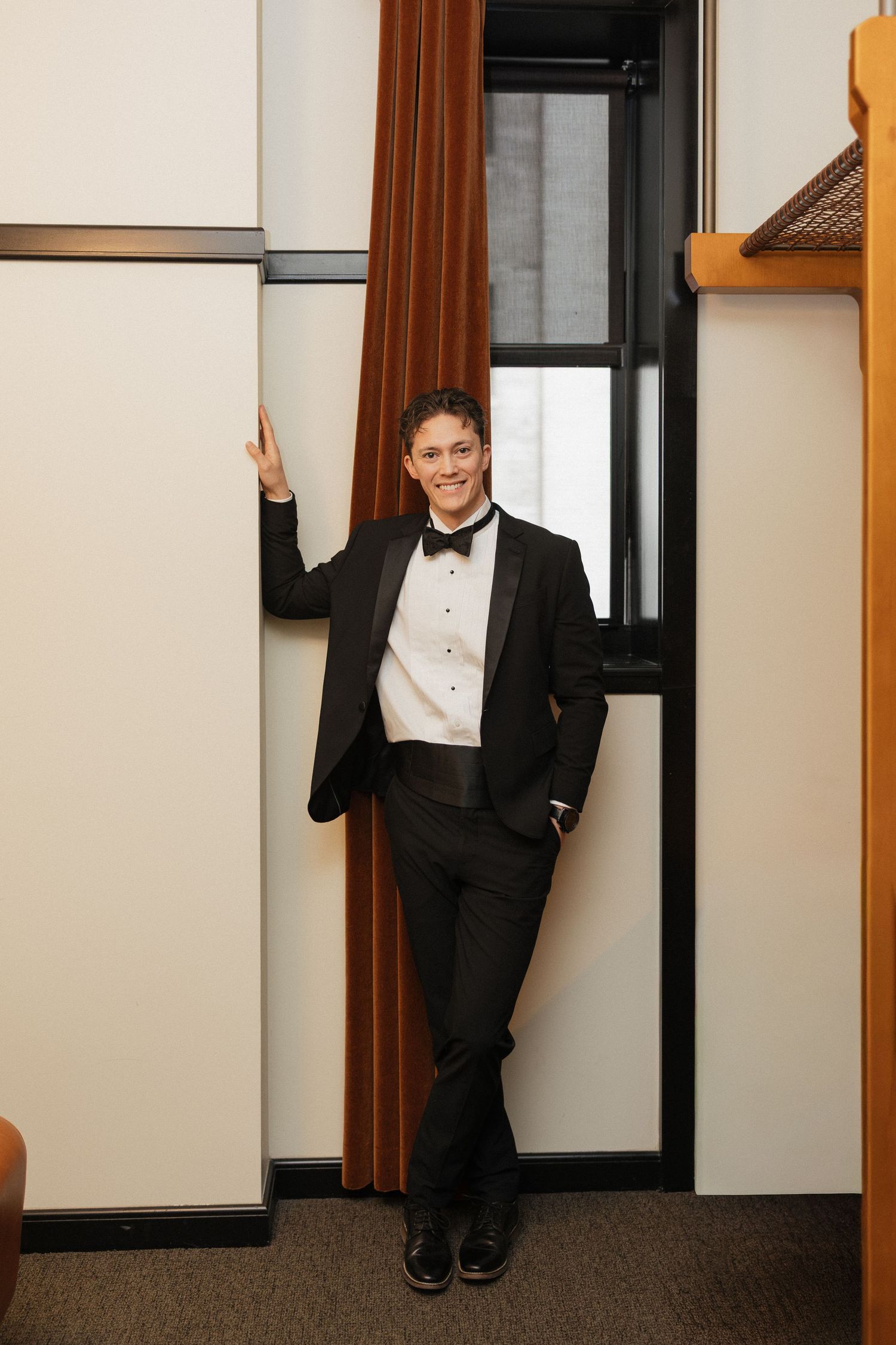 Playful wedding party poses in doorways of hotel hallway.
