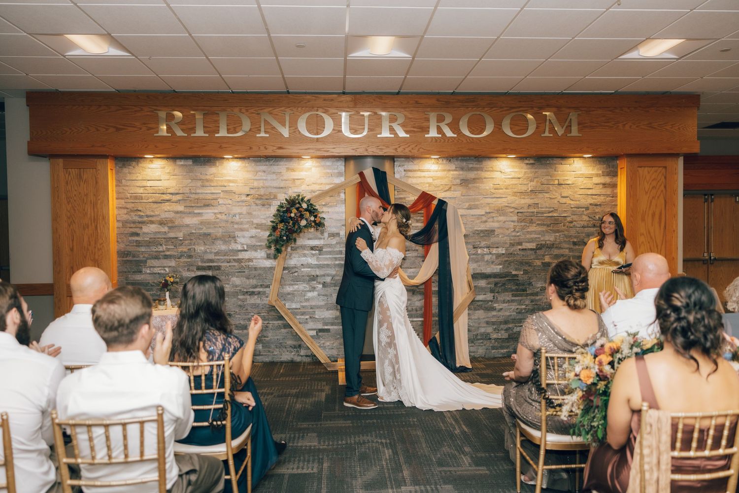 Wedding reception setup in an elegant room with stone accent walls and chiavari chairs.