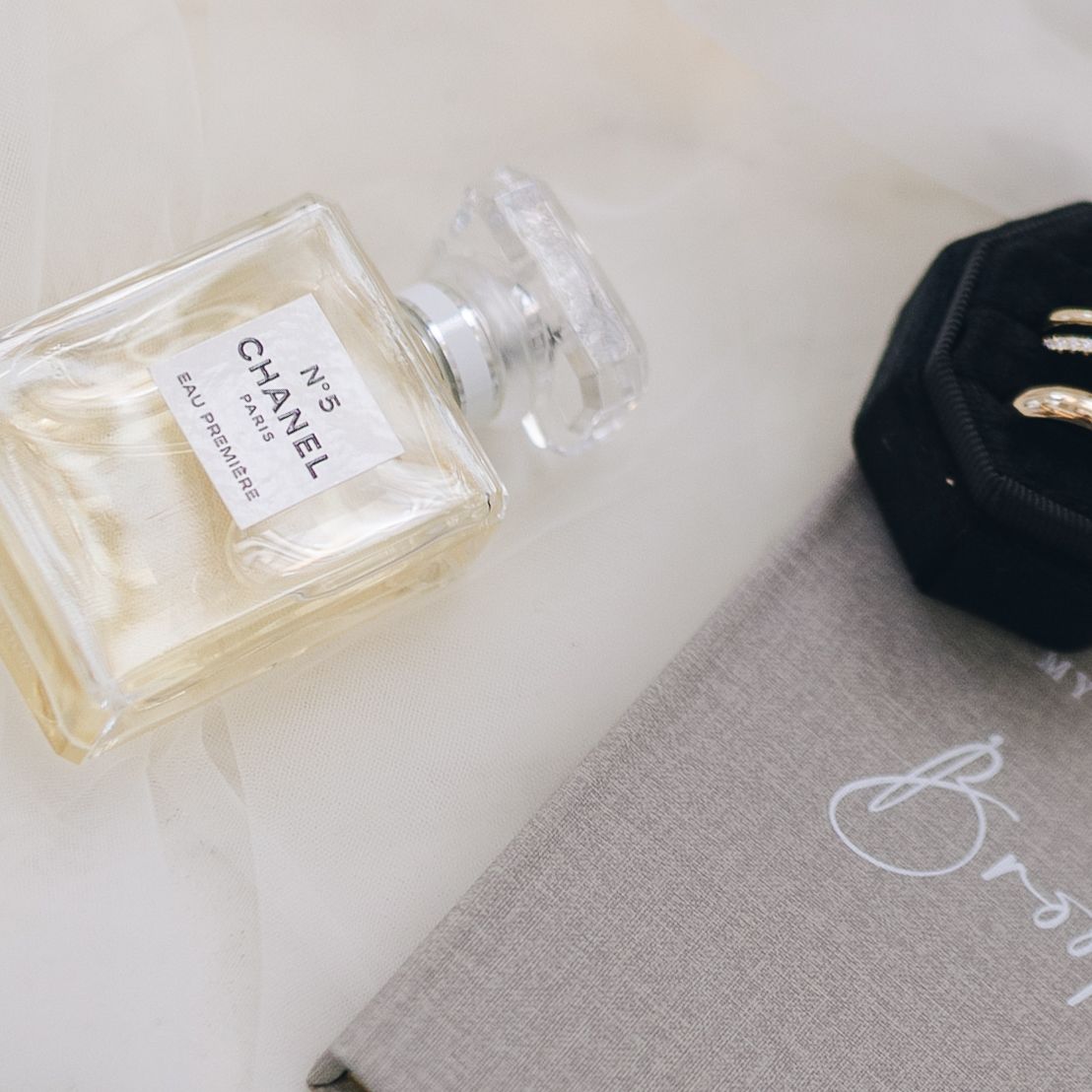 Luxury perfume bottles with gold and clear glass designs displayed on a light gray textured surface.
