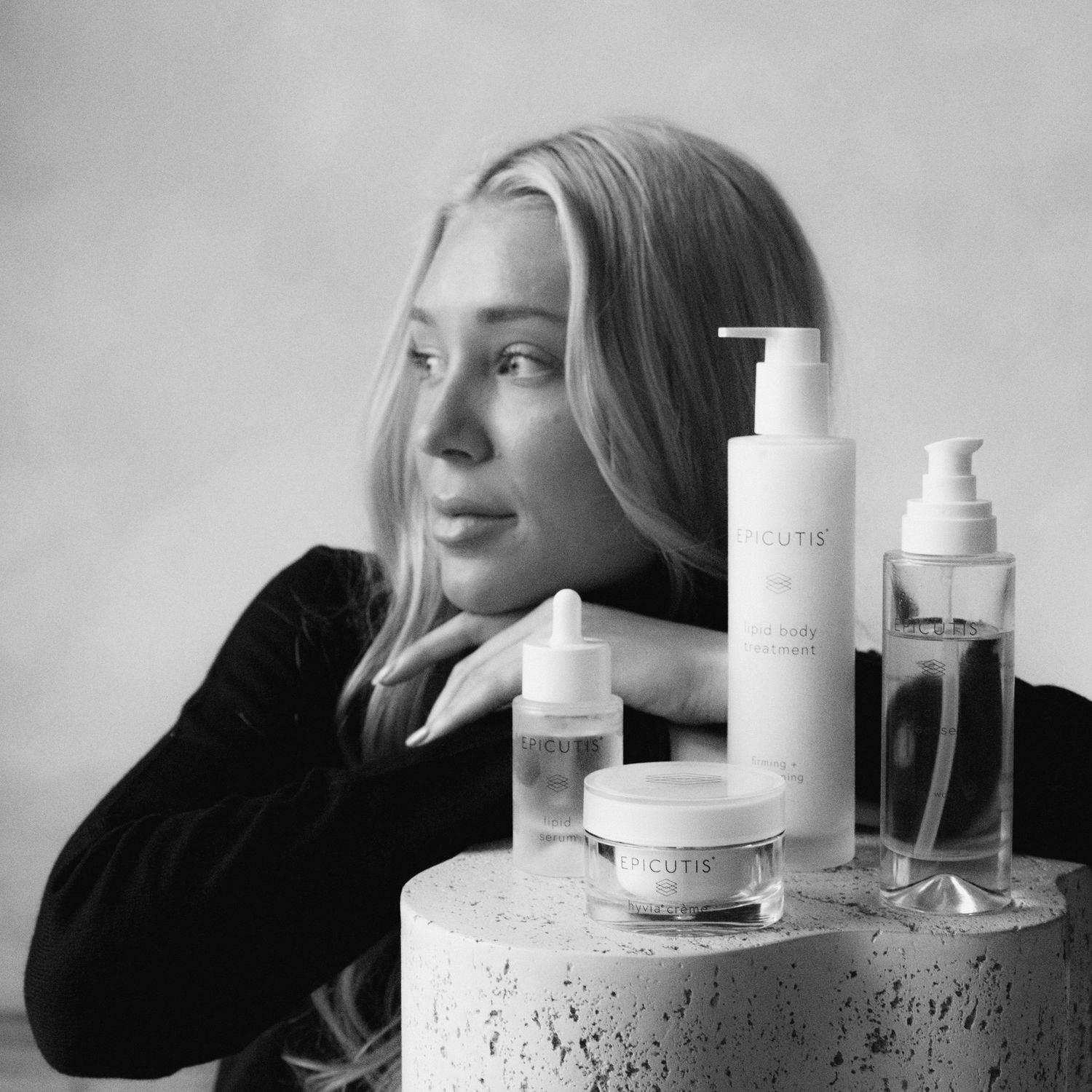 Monochrome product photography featuring skincare bottles arranged on concrete pedestals.