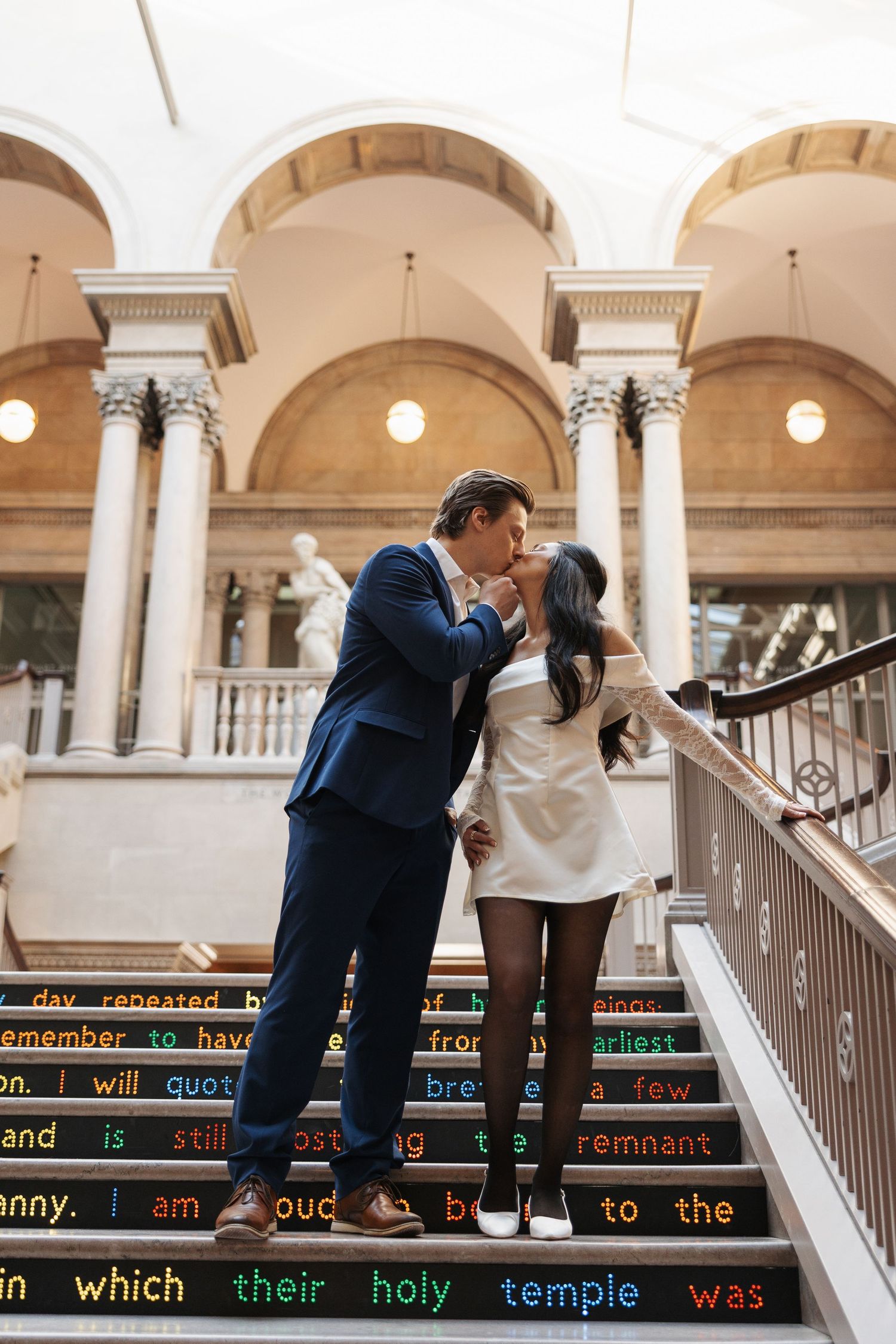 A couple shares playful moments on decorative stairs with text inscriptions.