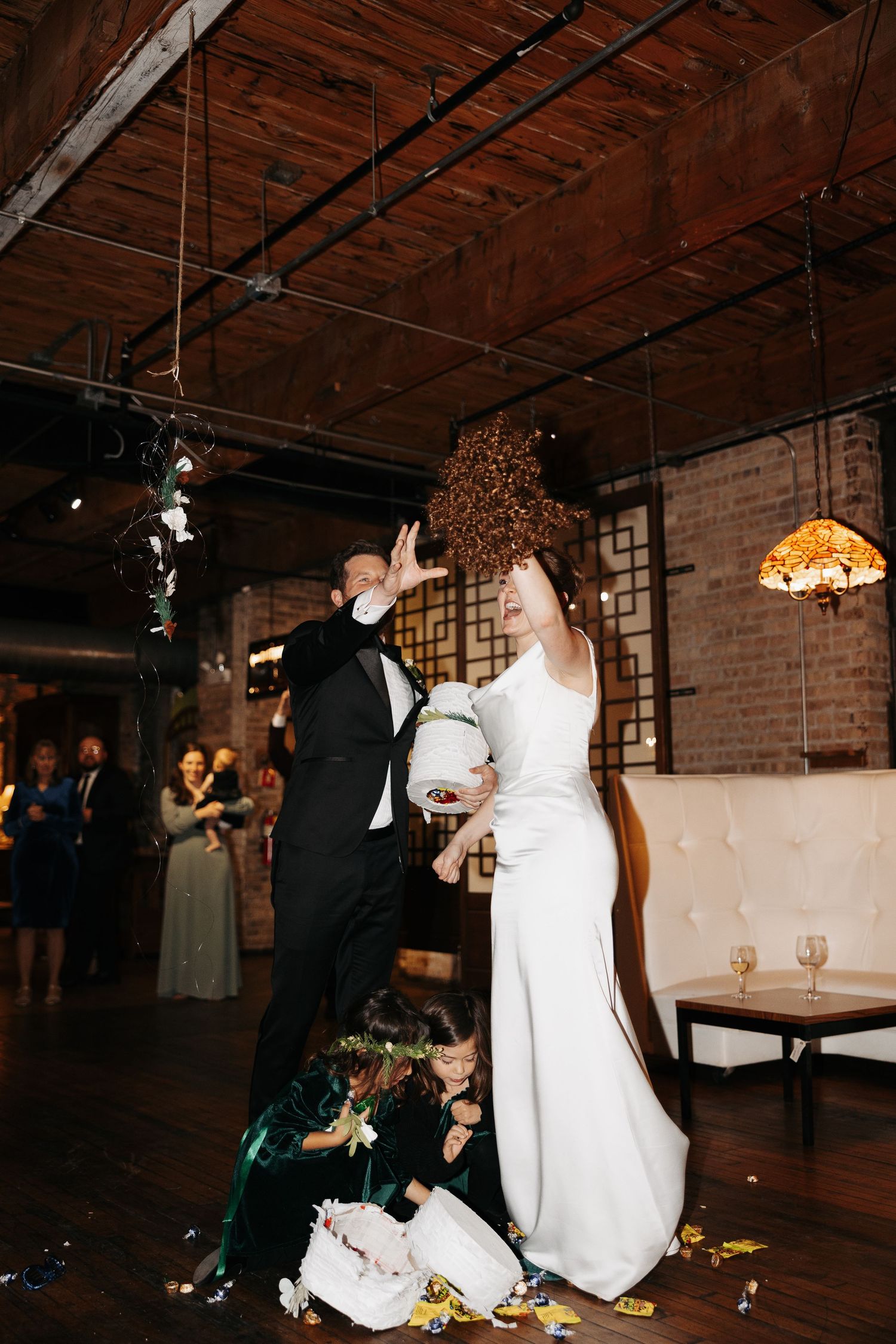 Newlyweds dance and celebrate during their first dance at a rustic brick-walled wedding reception venue.