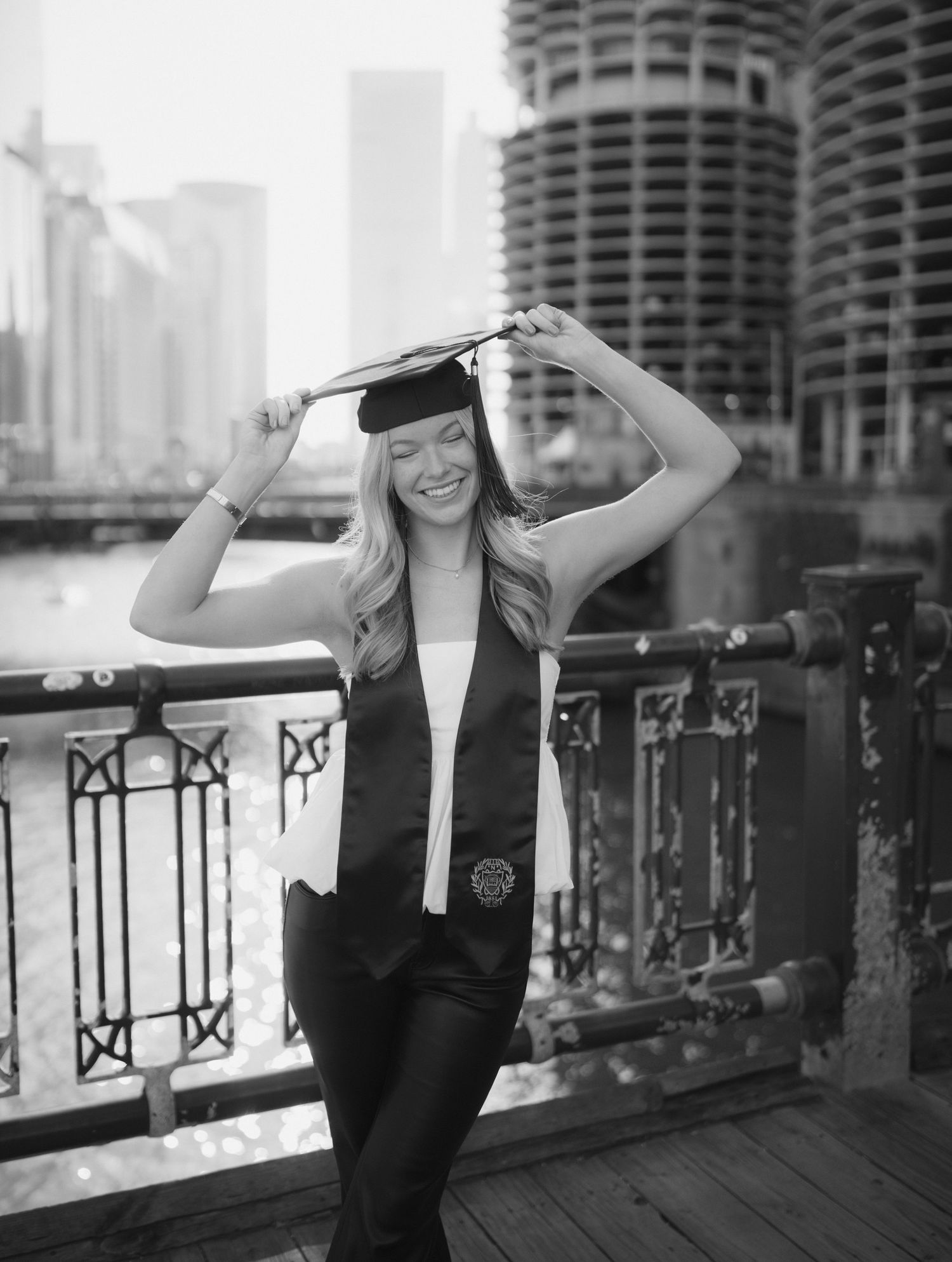A graduation photo taken on a riverfront boardwalk with the Marina City towers visible in downtown Chicago.