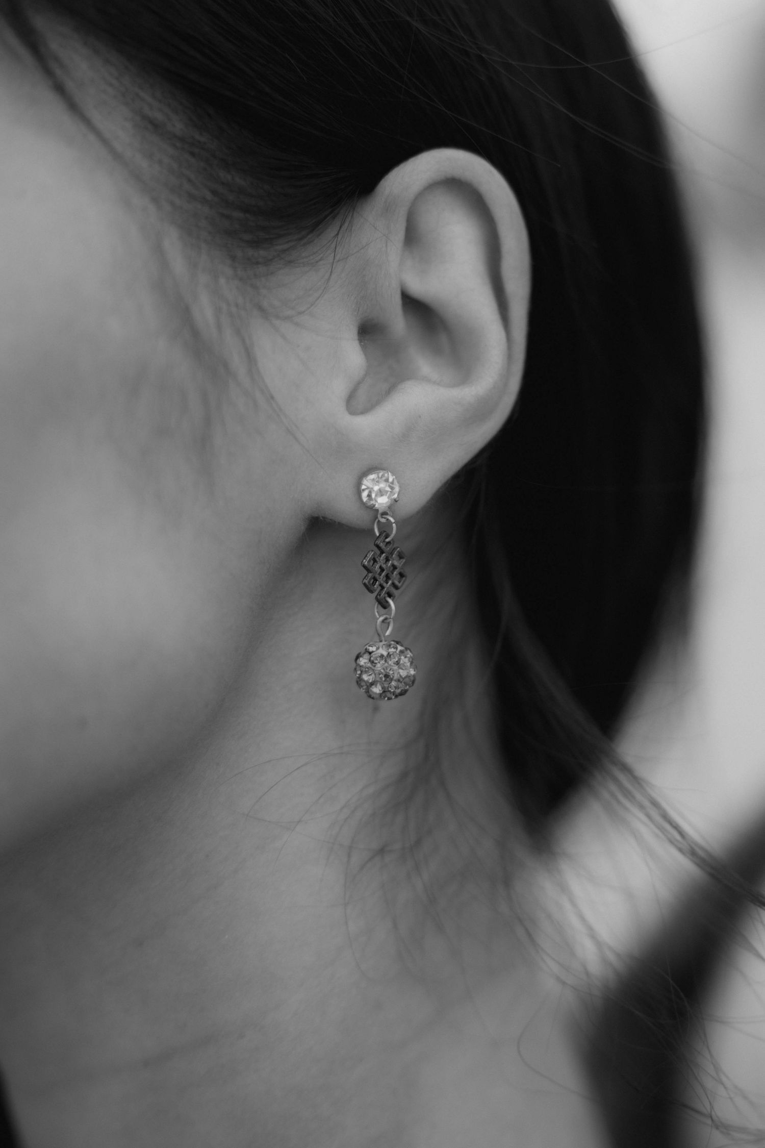 Close-up black and white photo of a woman wearing elegant crystal drop earrings with decorative charm.