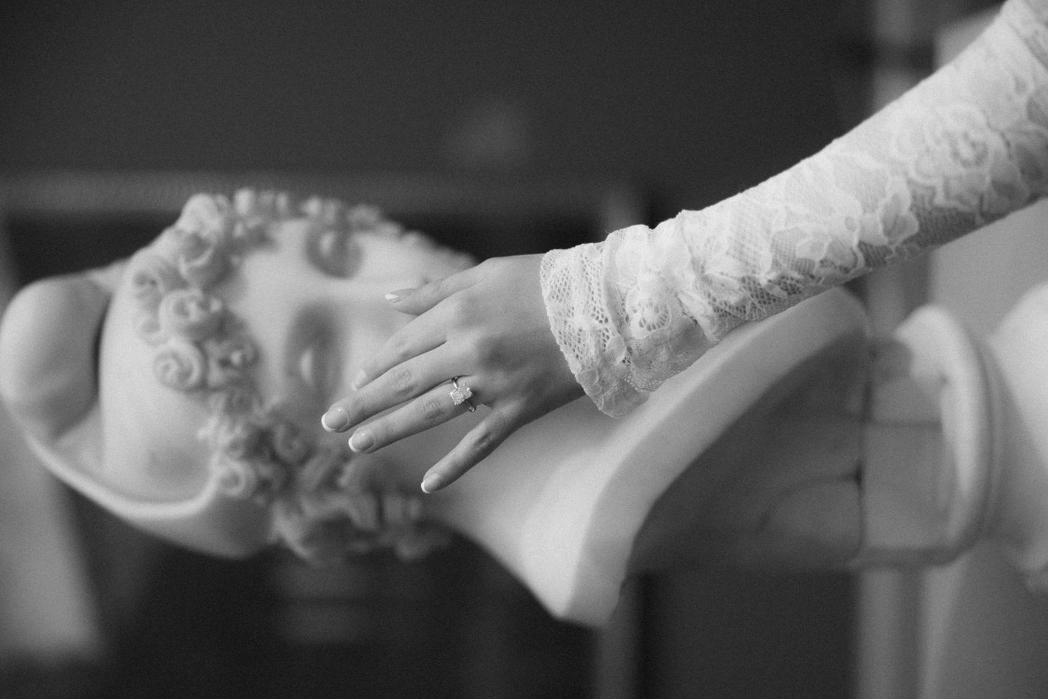 Close-up details of lace sleeves and hands with delicate jewelry.