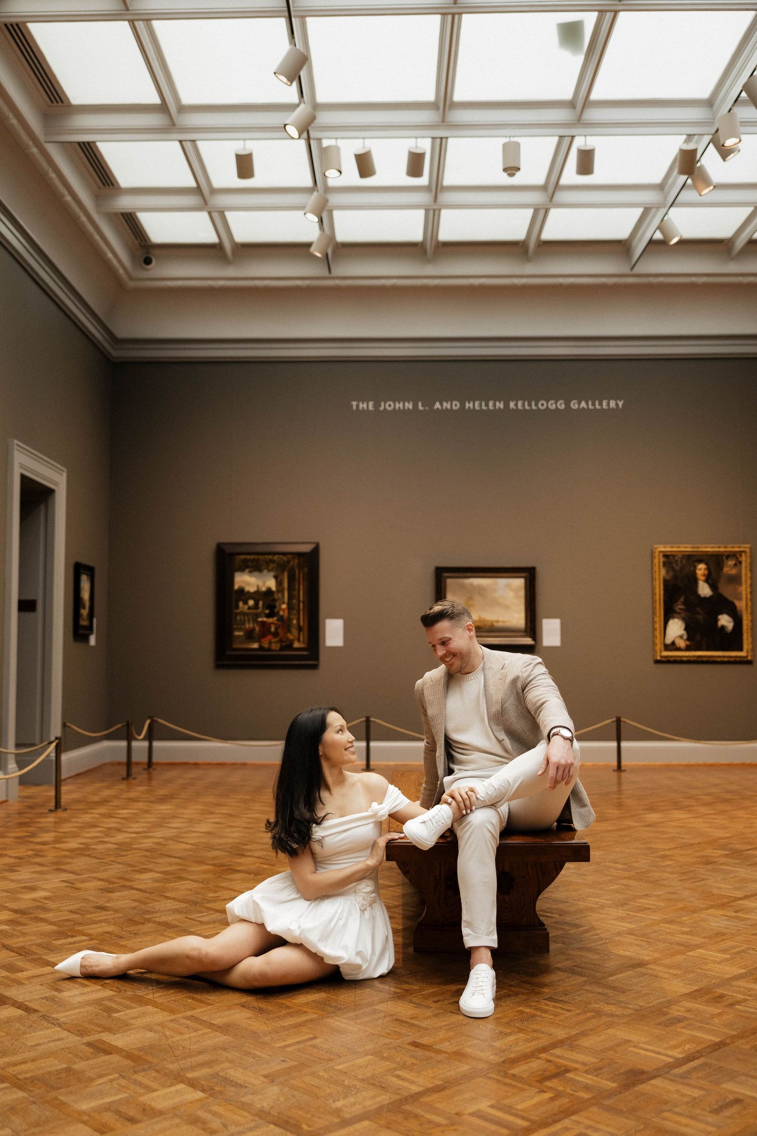 Couple shares a romantic moment in the John L. and Helen Kellogg Gallery, surrounded by classic paintings.