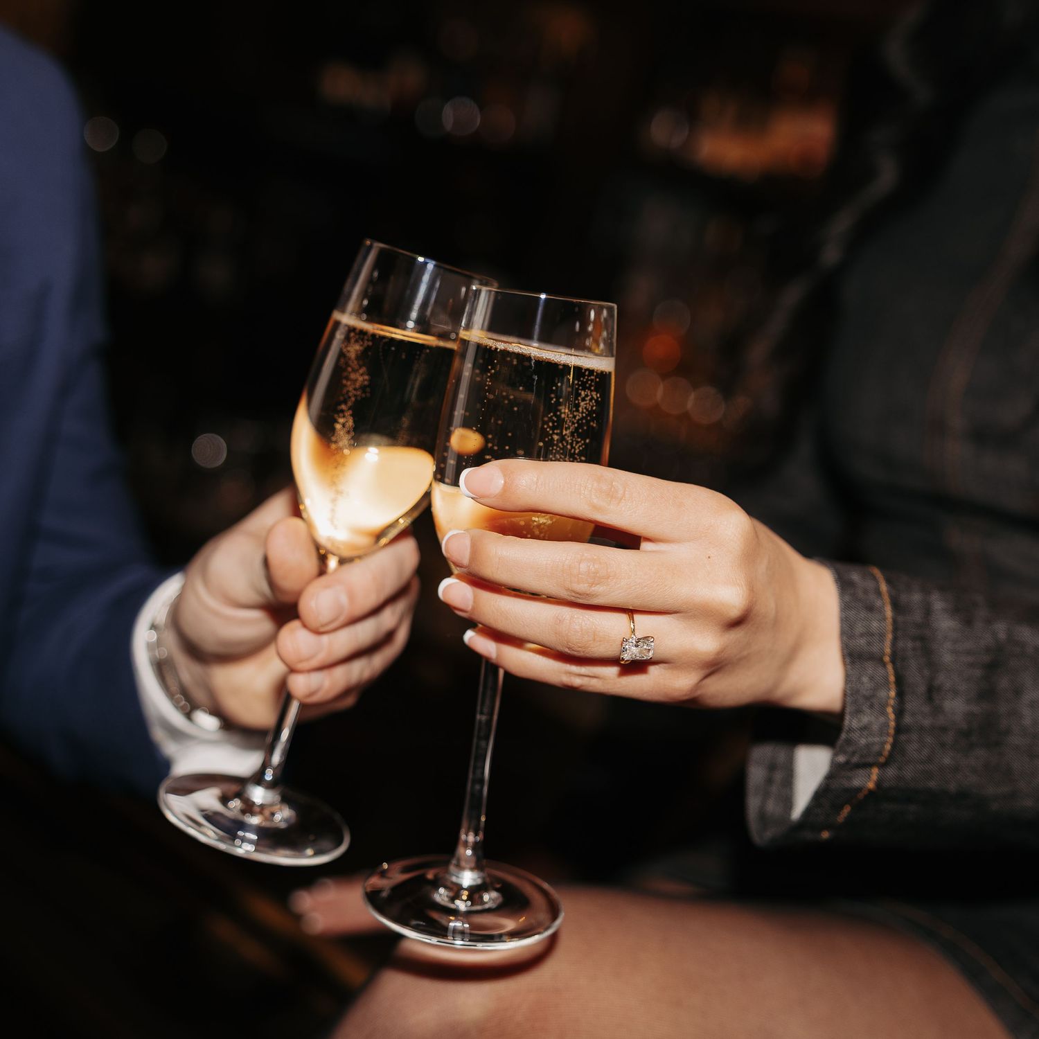 Two people toasting with champagne glasses in a dimly lit setting, creating a celebratory atmosphere.