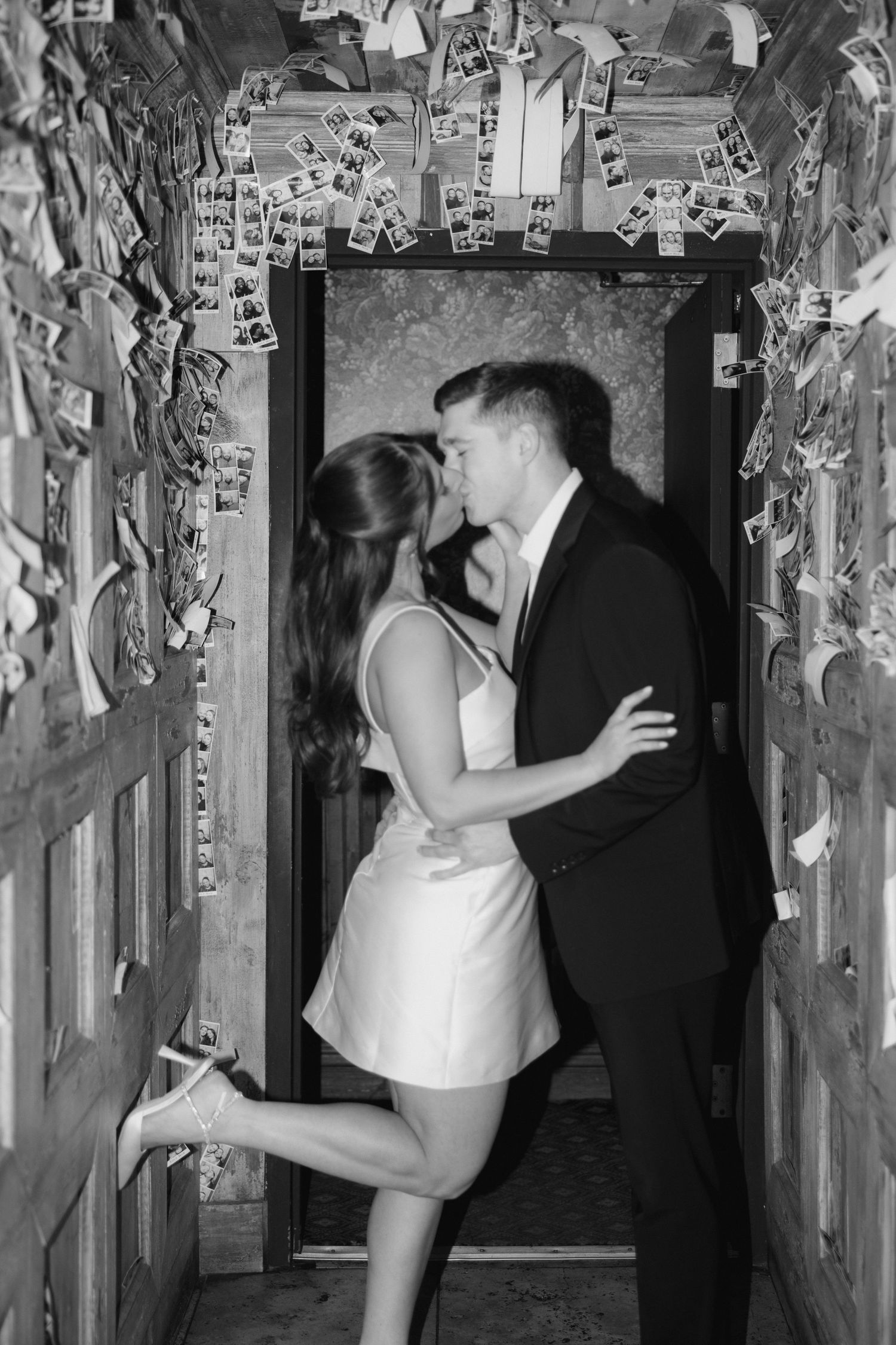 A couple shares romantic dance poses in a hallway decorated with hanging silver streamers.