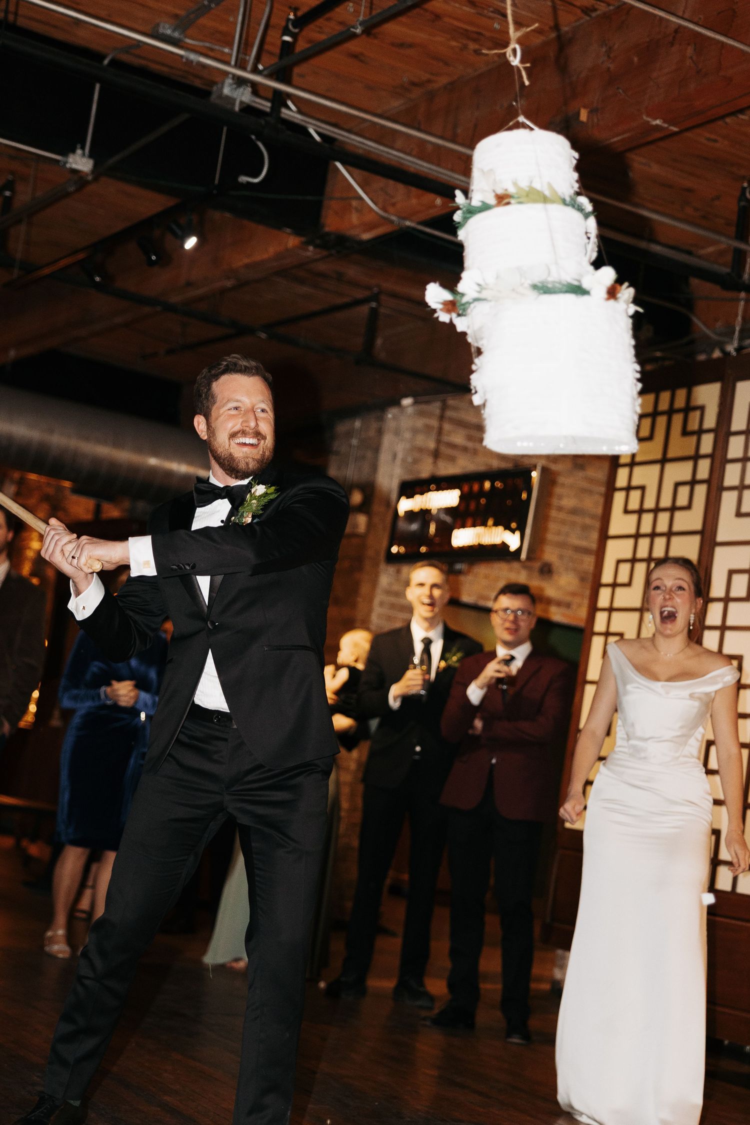 A couple performs a playful dance move with the bride being dipped during their wedding reception in a rustic venue.