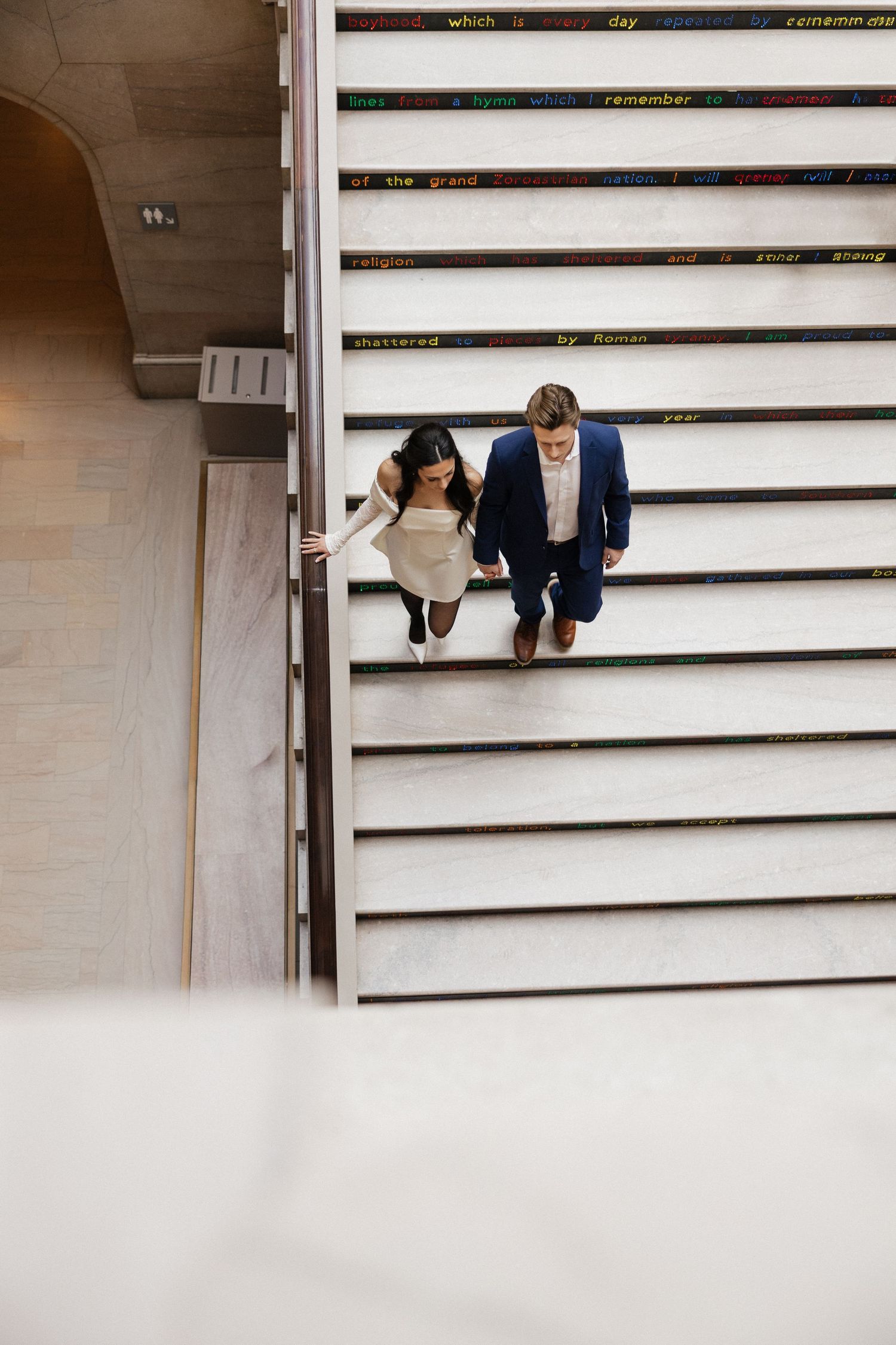People walking down geometric white steps in an architectural setting.