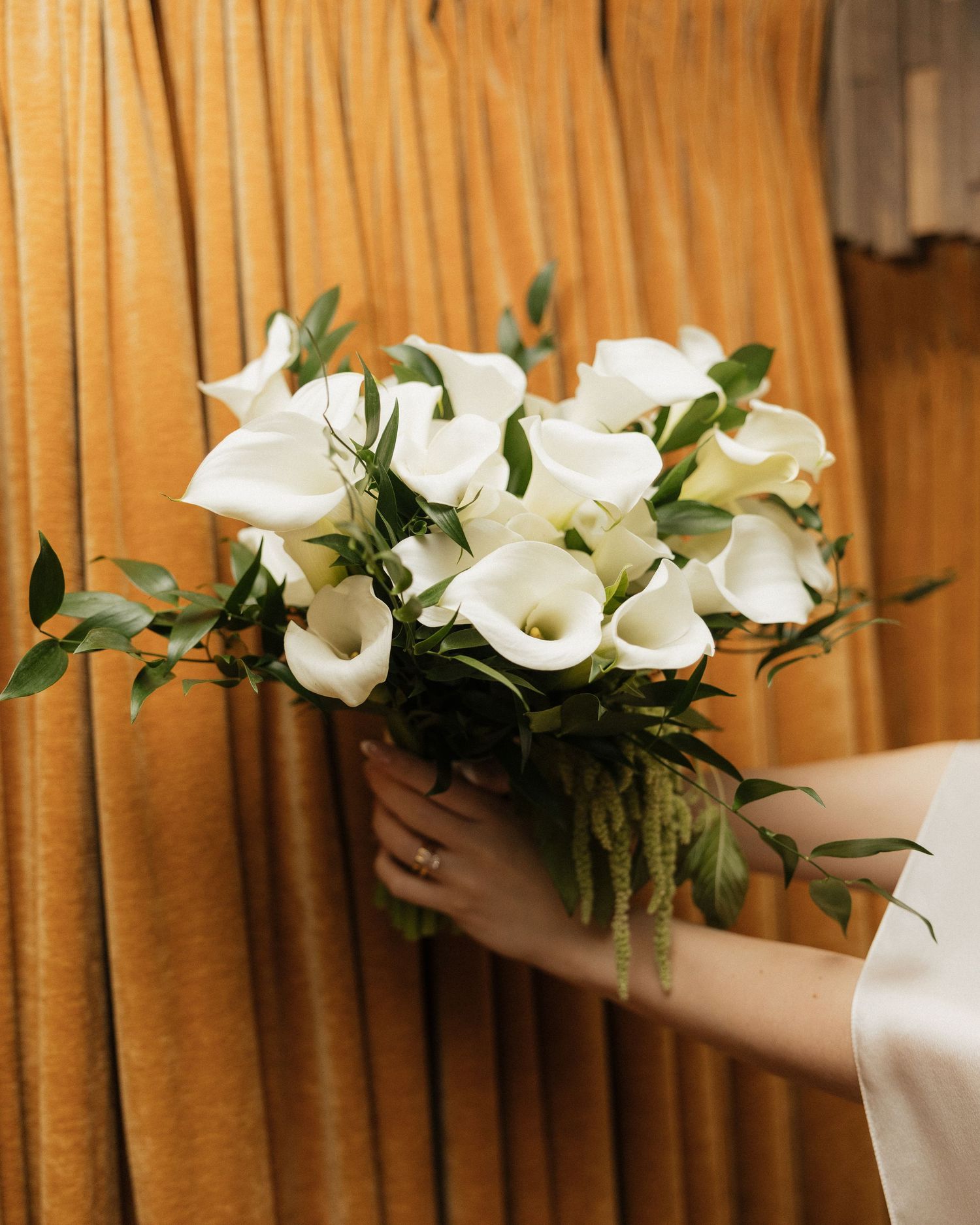 A row of white calla lilies and greenery arranged as wedding decorations.