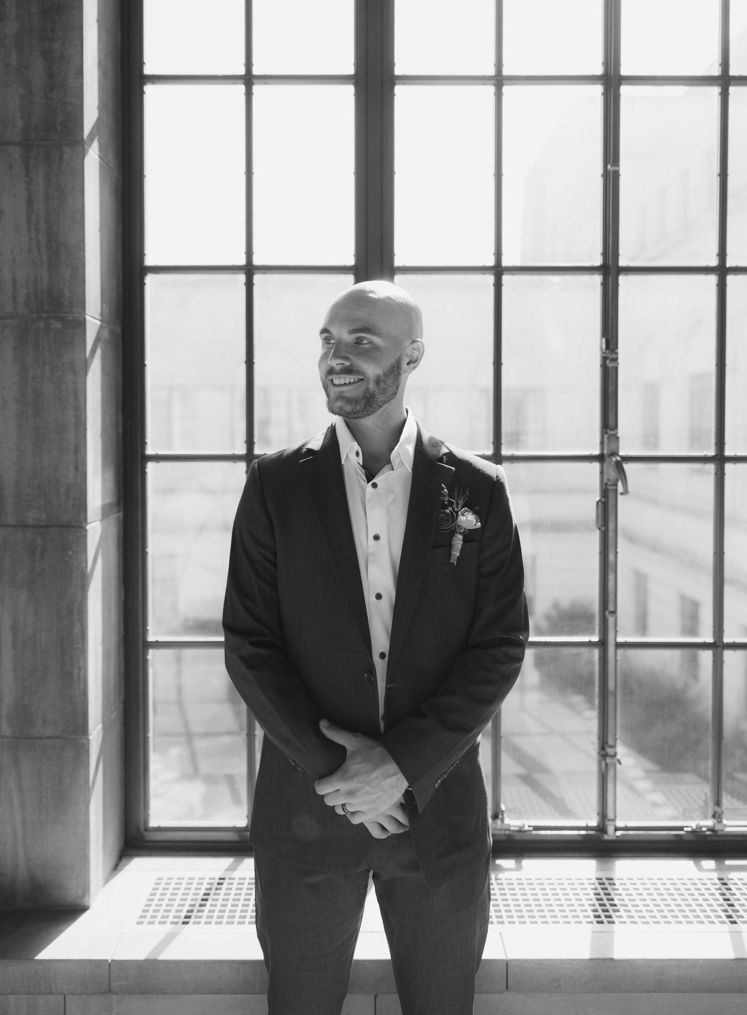 Groom portraits by large windows in classic architectural setting.
