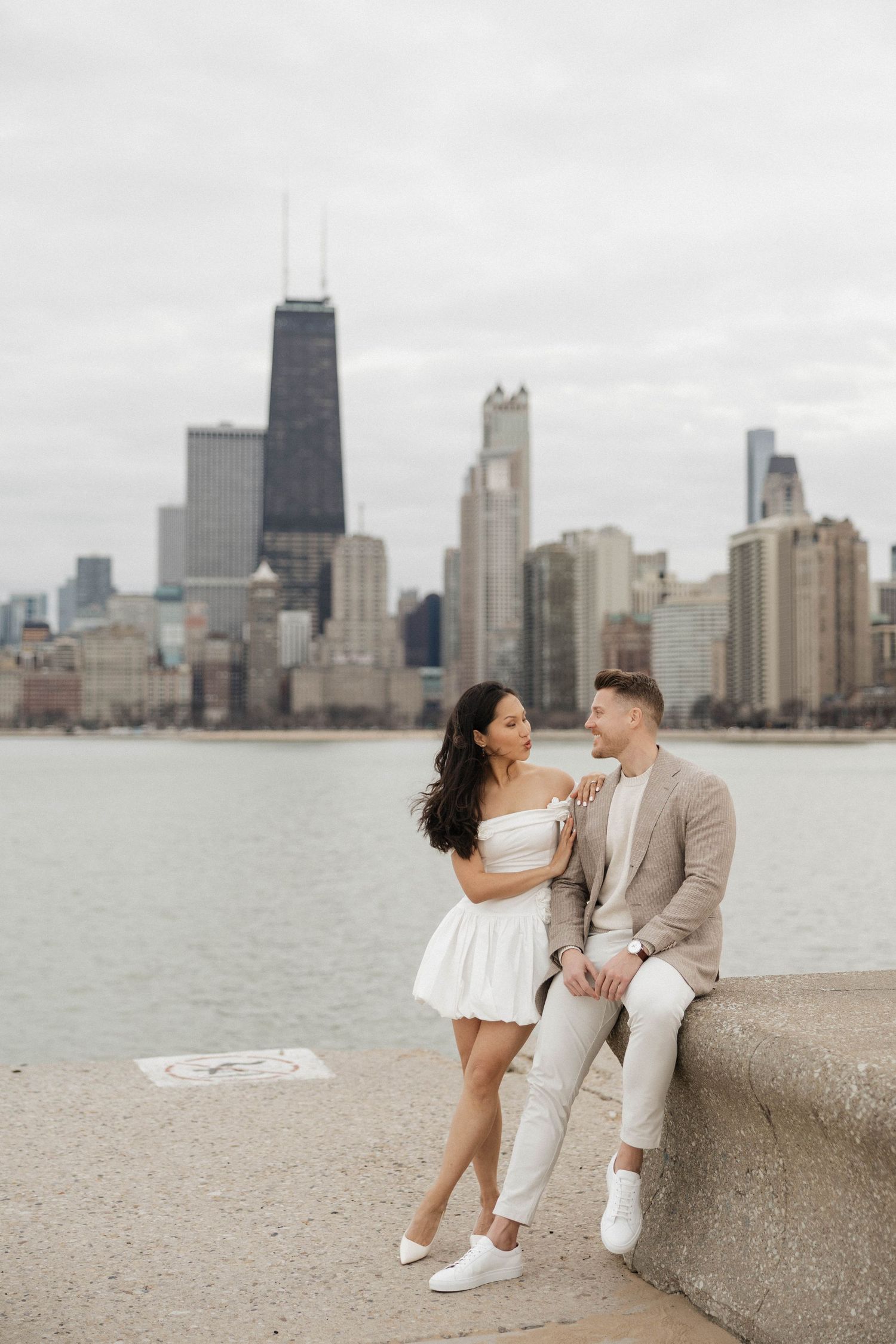 Couple posing together by Lake Michigan with Chicago city skyline backdrop.