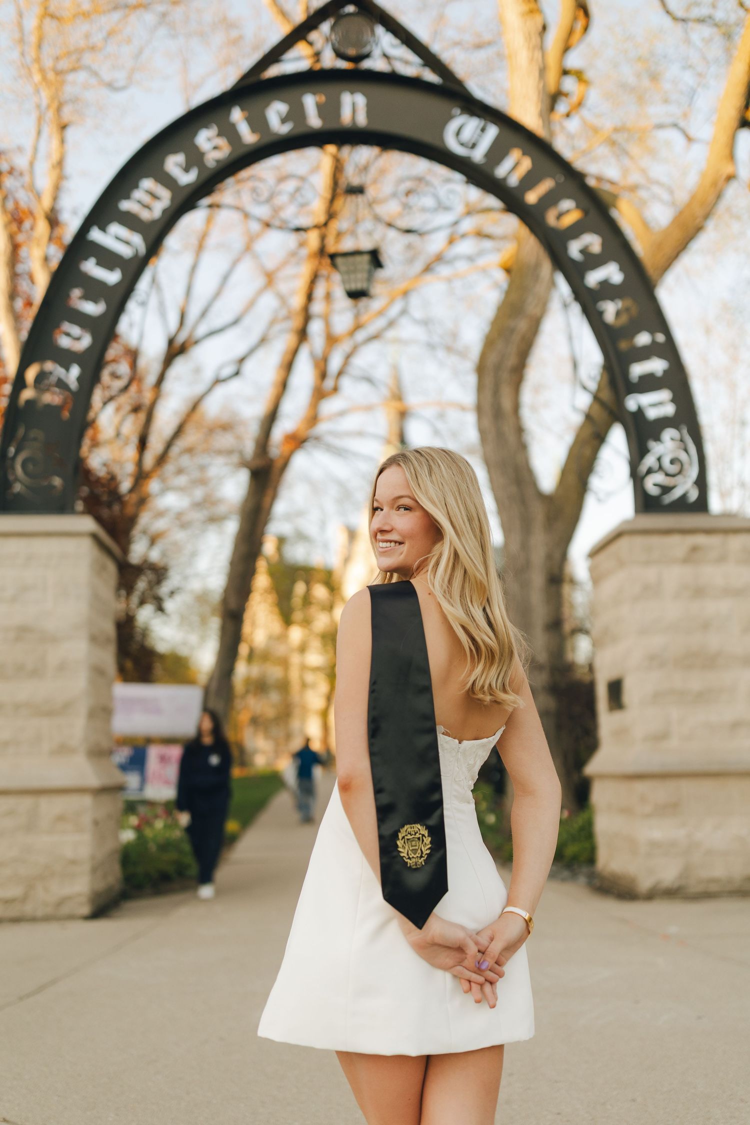 A series of five photos showing someone in a black and white outfit posing playfully against stone archways at sunset.
