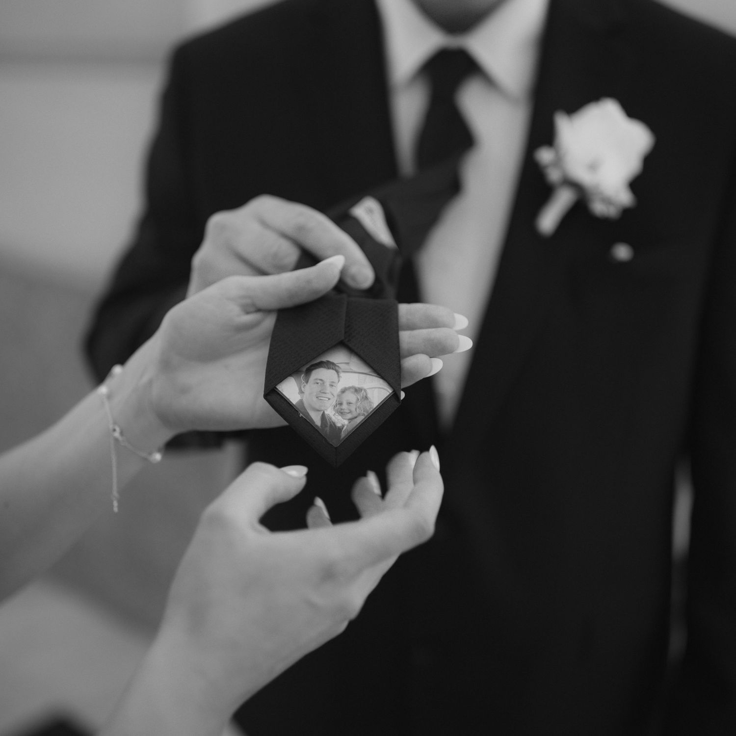 Black and white close-up of hands exchanging wedding rings during a marriage ceremony.