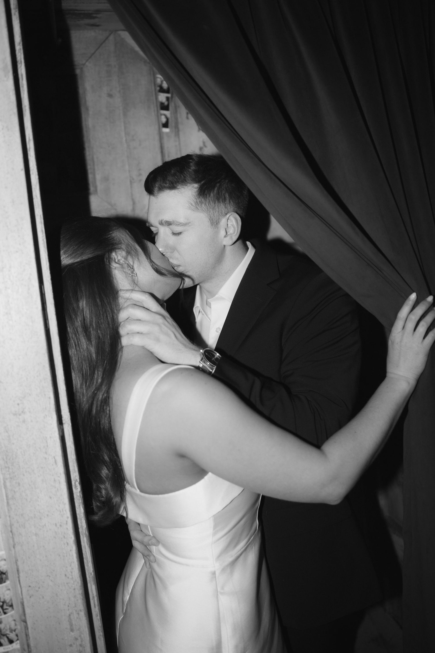 Black and white photo series showing a romantic couple sharing intimate moments behind curtains at a party or event.