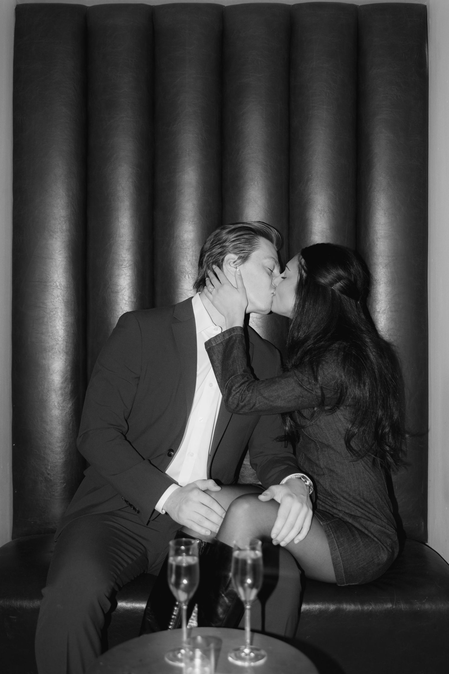 A romantic black and white photo of a couple sharing an intimate moment on a lounge sofa.