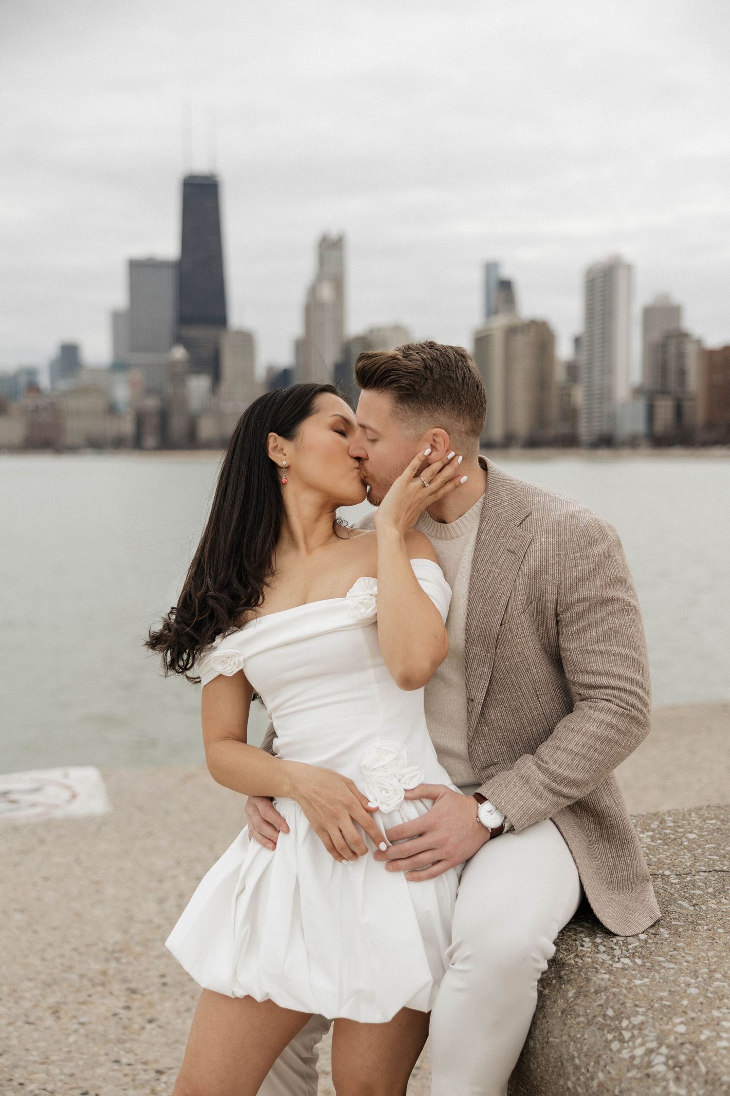Couple sharing a romantic kiss with Chicago skyline and Lake Michigan in the background.