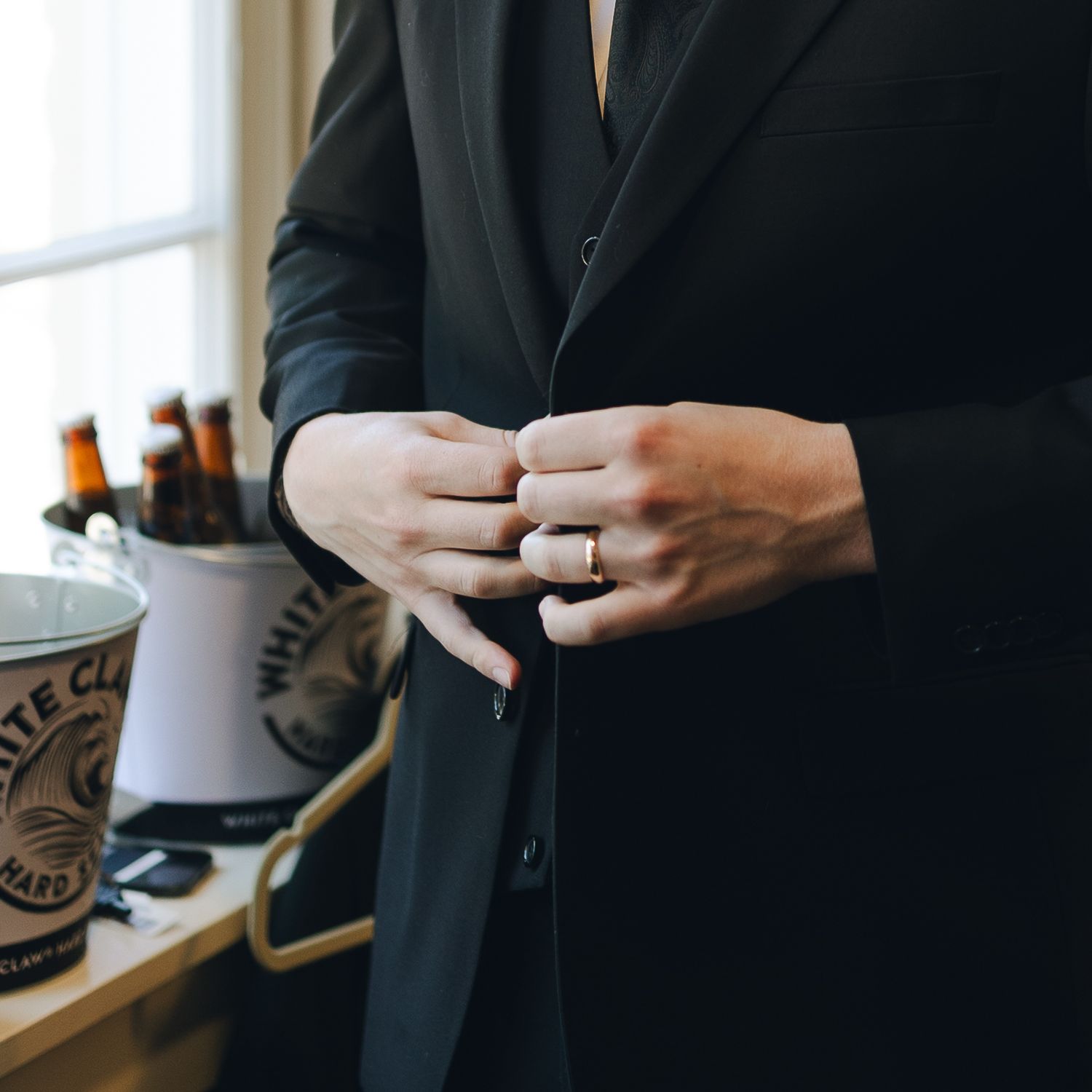 Close-up shot of hands wearing a wedding ring while holding a coffee cup near a window.