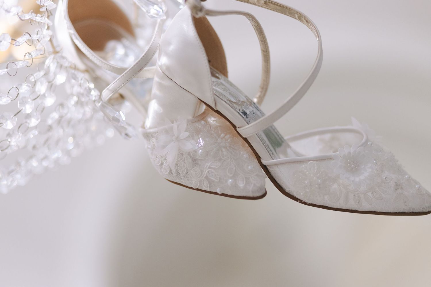 Close-up detail of a crystal chandelier's delicate beading and ornate metalwork in soft lighting.