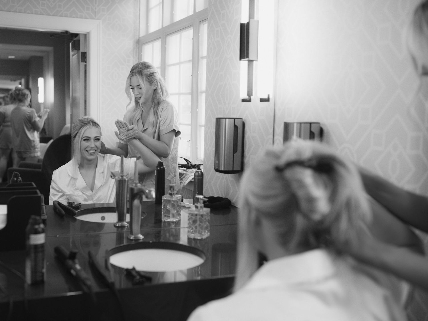 A series of black and white photographs showing people working and interacting in a bright, window-lit interior space.