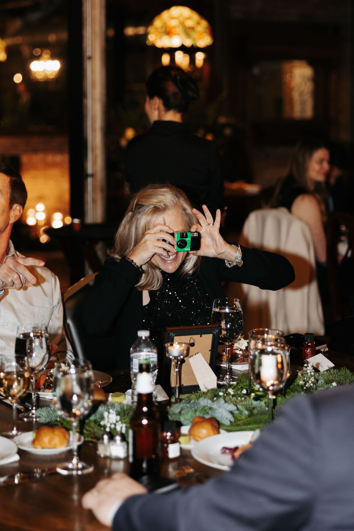 People dining at an elegant dinner party with candlelight and wine glasses on a decorated table.