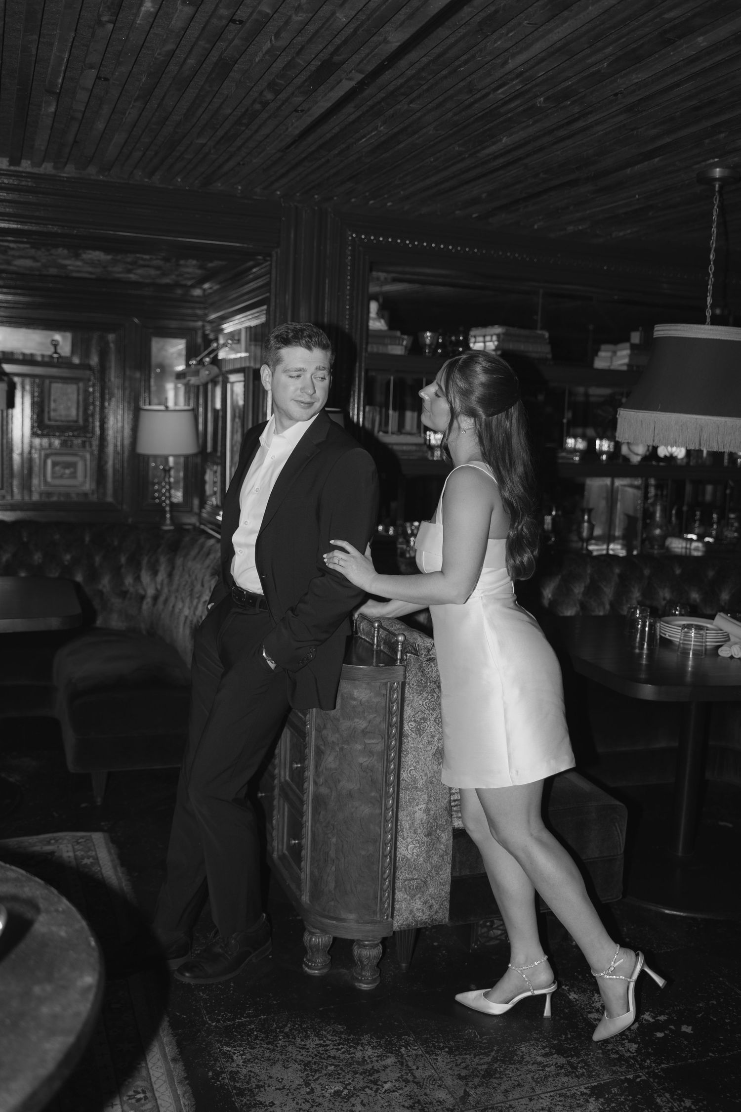 A couple dancing together in a dimly lit room with dark wooden floors and walls.