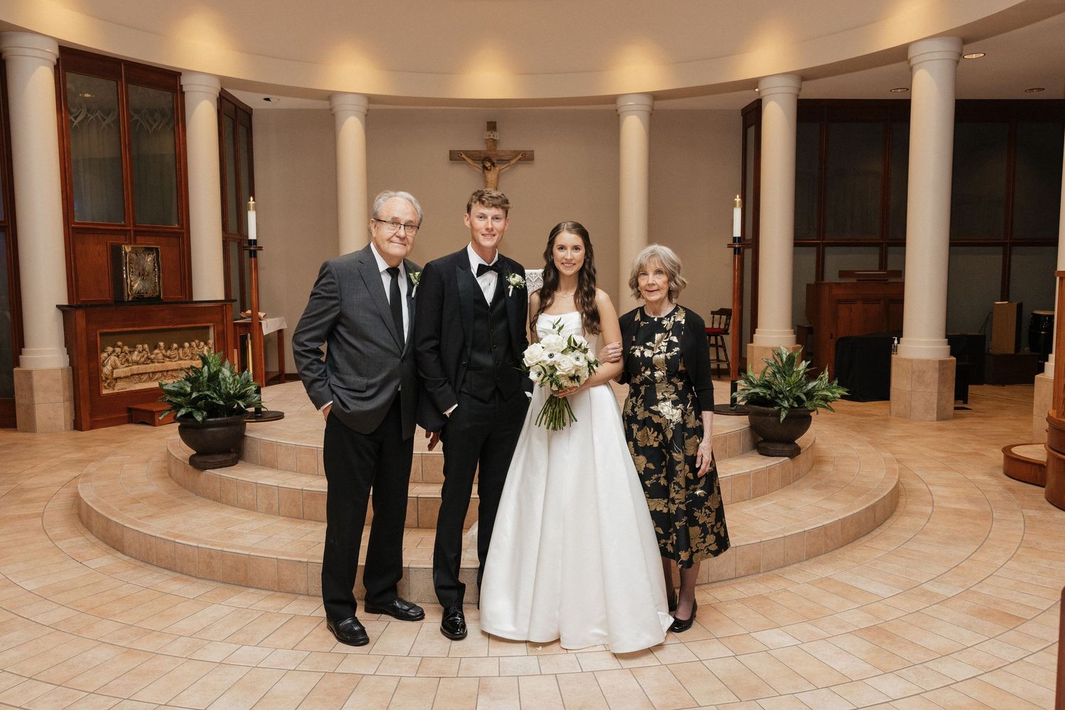 Bride and groom pose with family inside elegant church chapel after wedding ceremony.