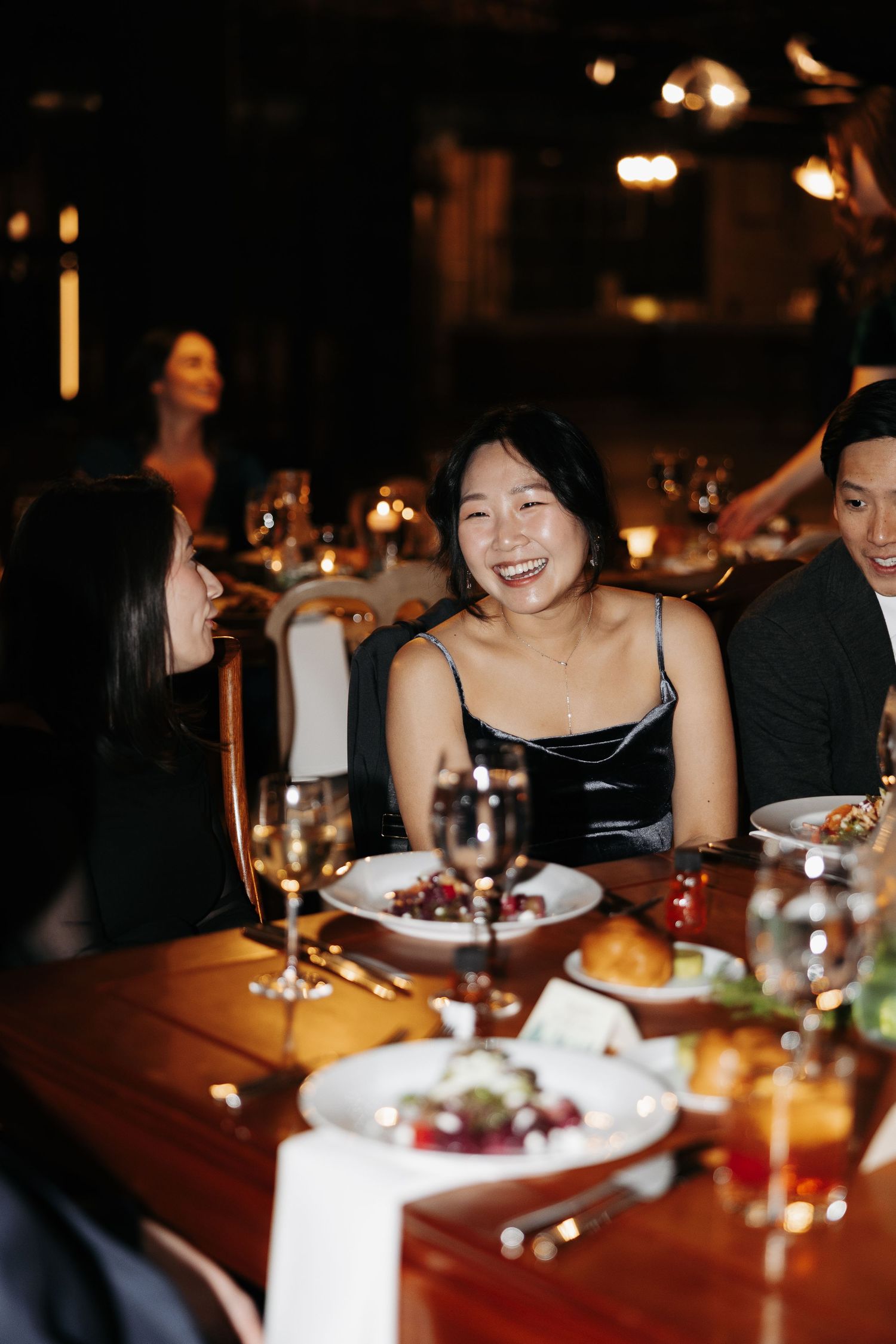 Diners enjoying an intimate dinner at a dimly lit upscale restaurant with wine glasses and elegant place settings.