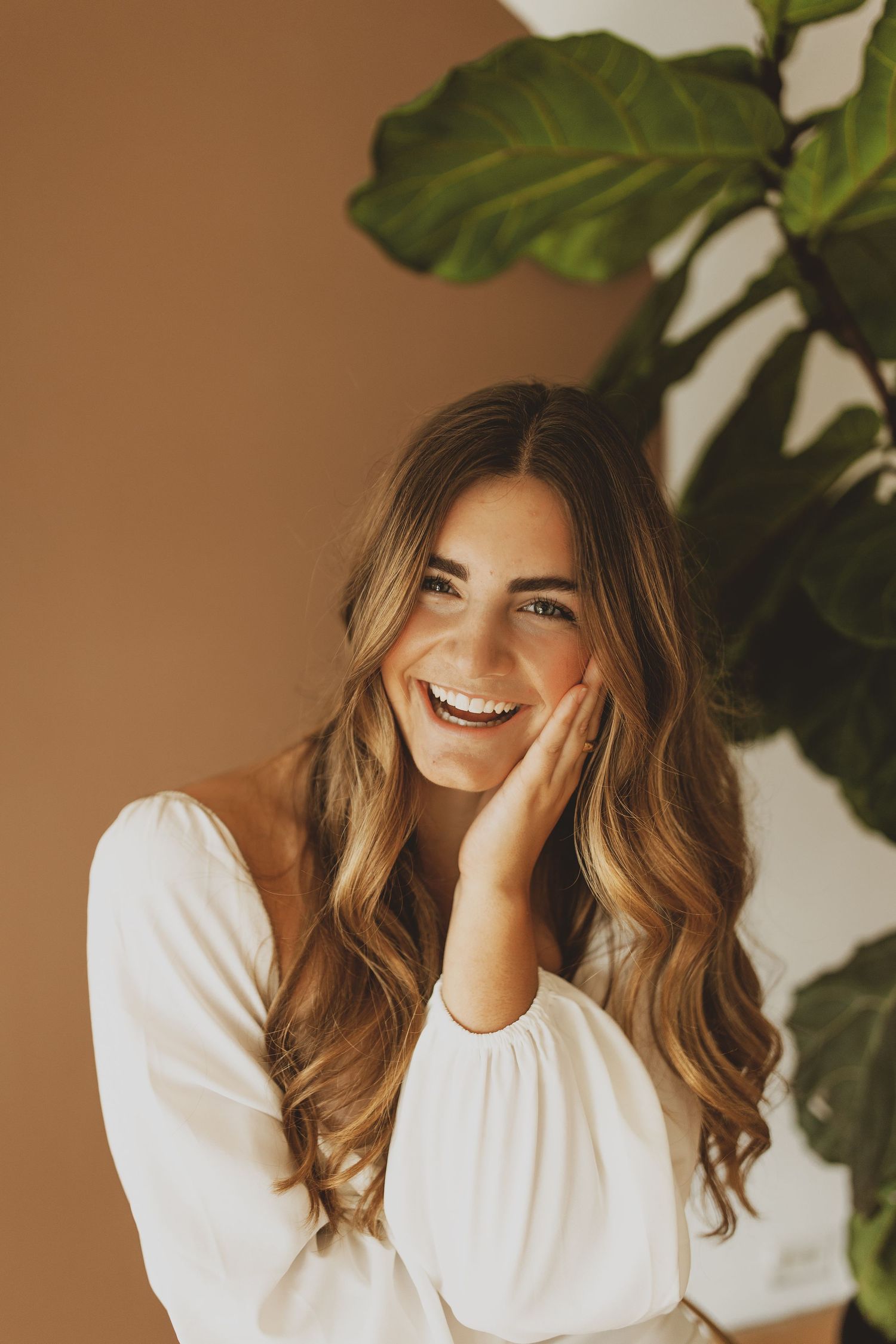 Portrait with warm lighting and large tropical plant leaves in the background.