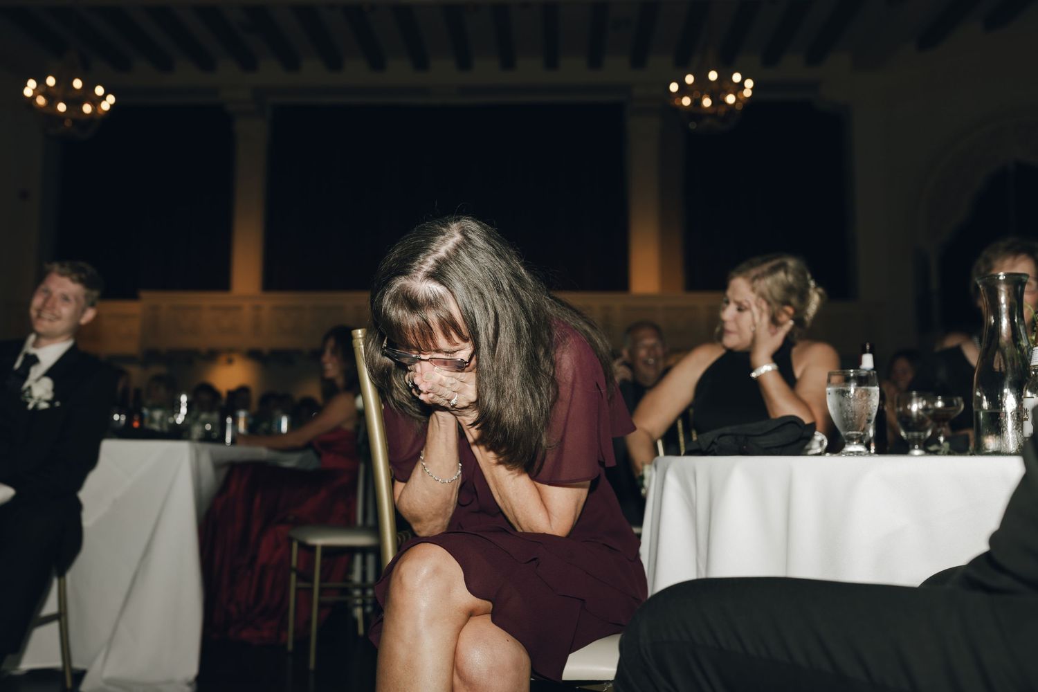 Wedding reception guests dancing and celebrating in a dimly lit venue.